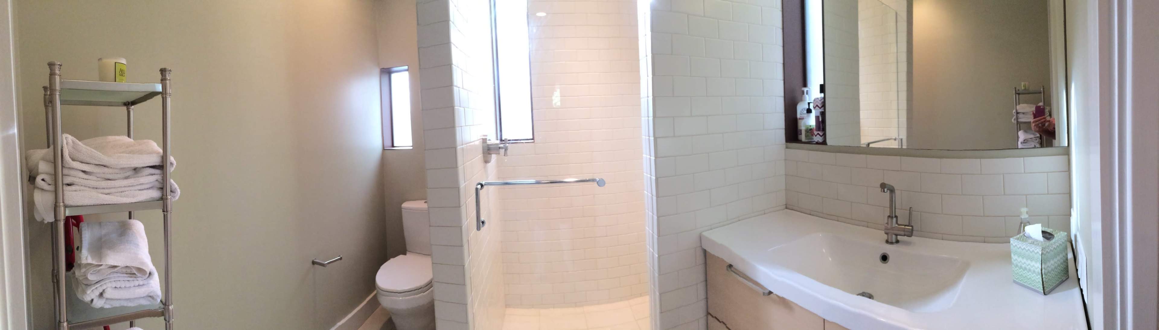 A modern bathroom featuring a bathtub, a toilet, a sink with a mirror, and a towel rack stocked with neatly folded towels.