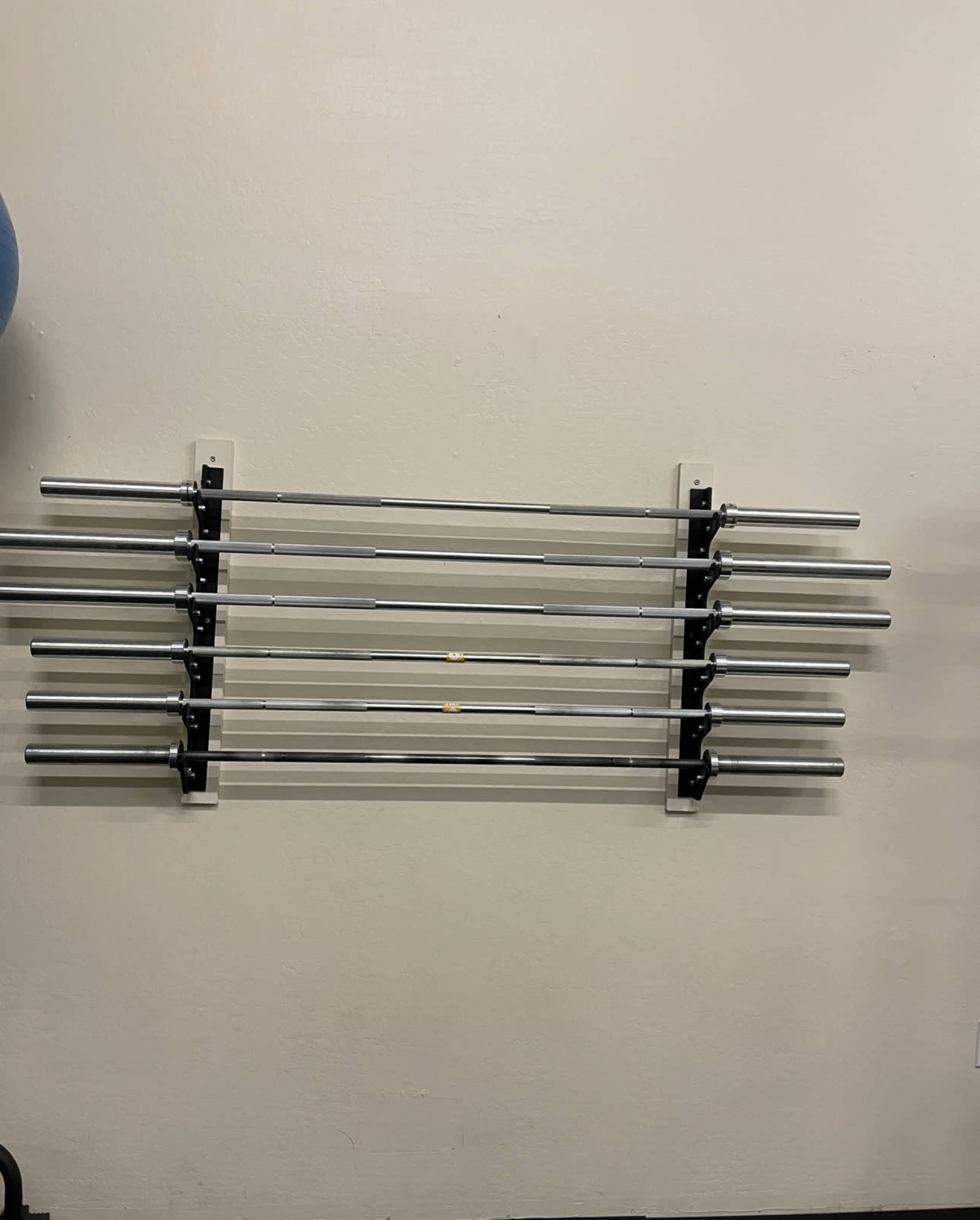 A set of metal weightlifting bars is mounted on a wall in a gym.