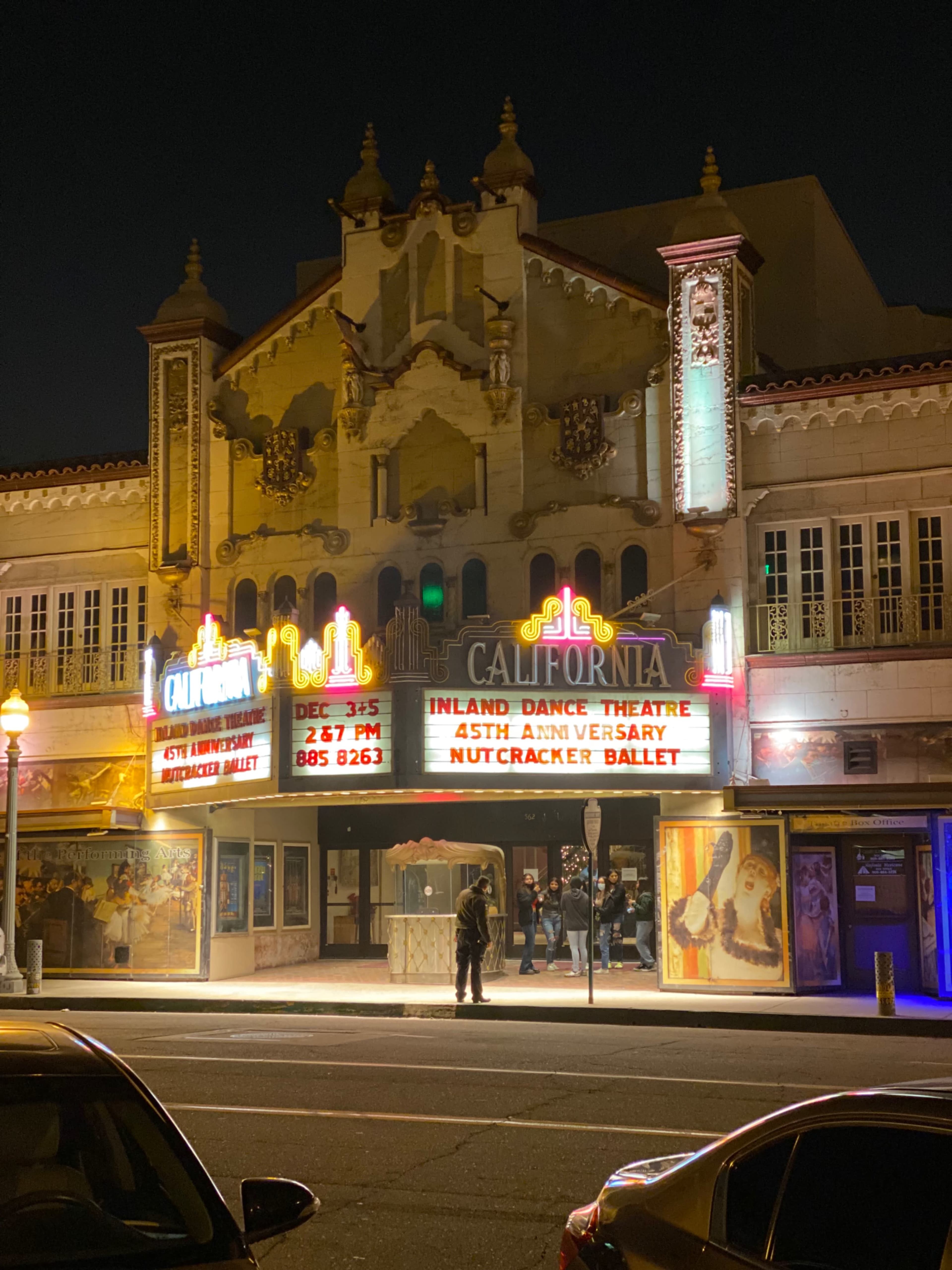 The California Theatre, illuminated with colorful marquee lights, showcases a performance of the Nutcracker Ballet on its main sign amidst a nighttime setting.