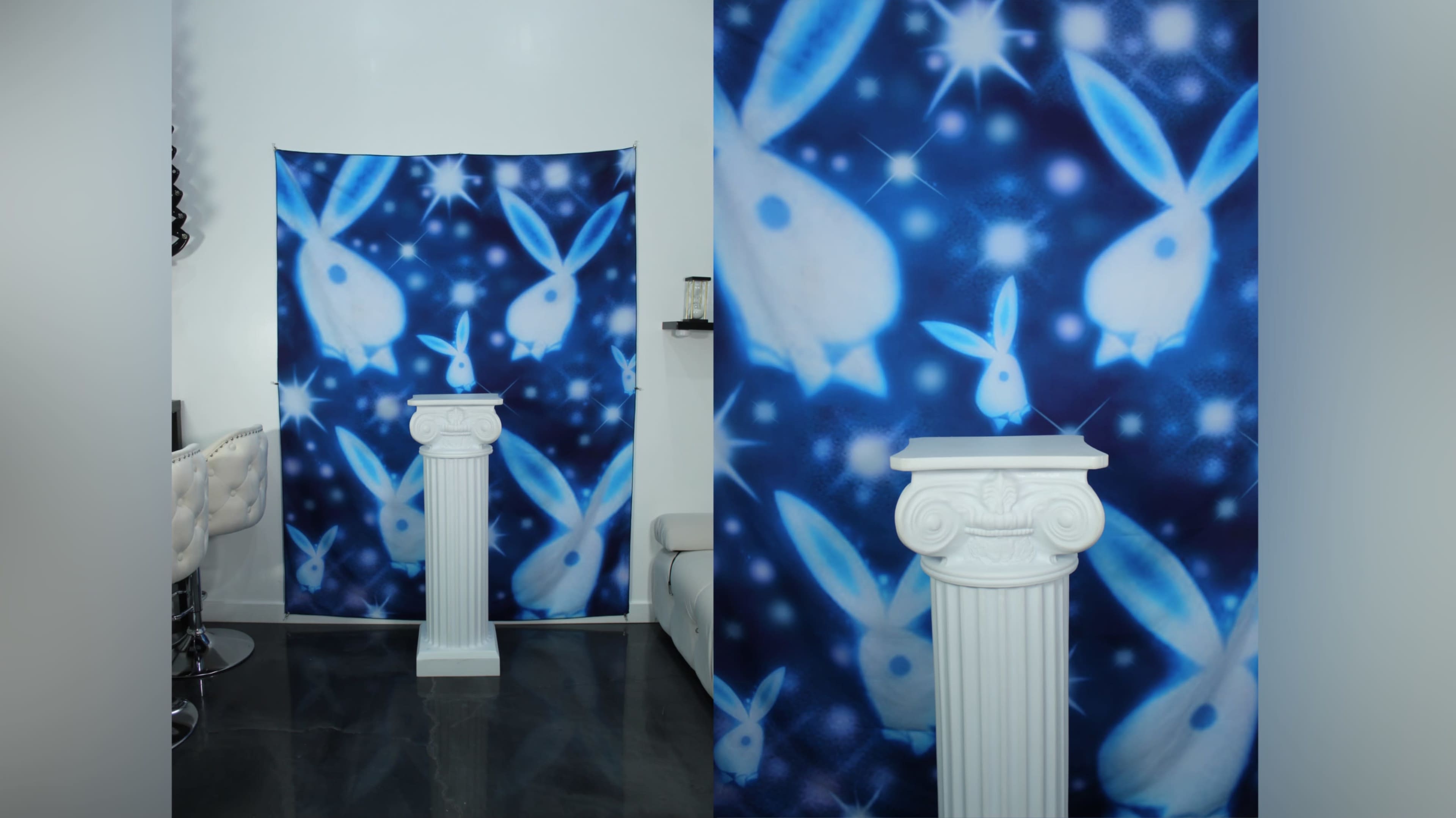 A room with a backdrop featuring white rabbits on a blue background and a white column placed in front of it.