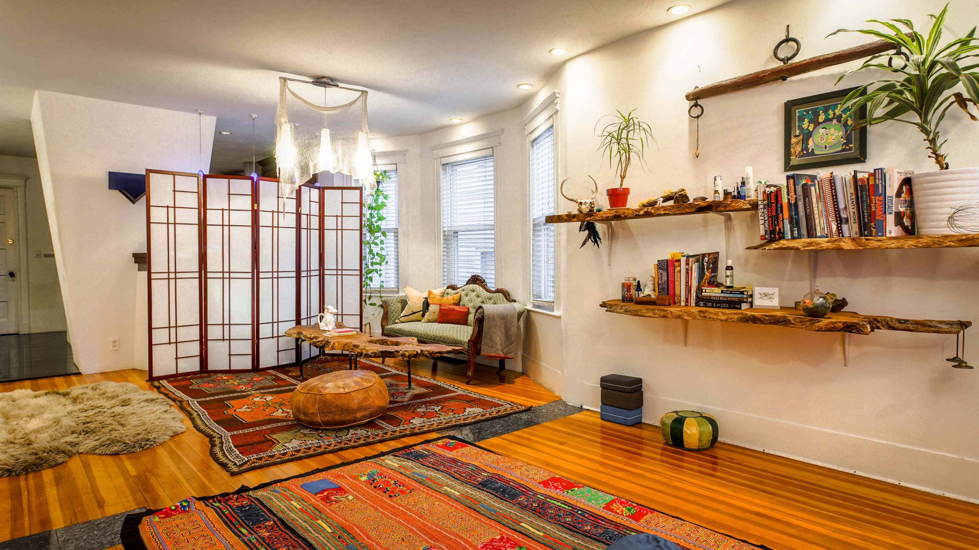 The room features a cozy seating area with a sofa, bookshelves mounted on the walls, and vibrant area rugs on hardwood flooring.