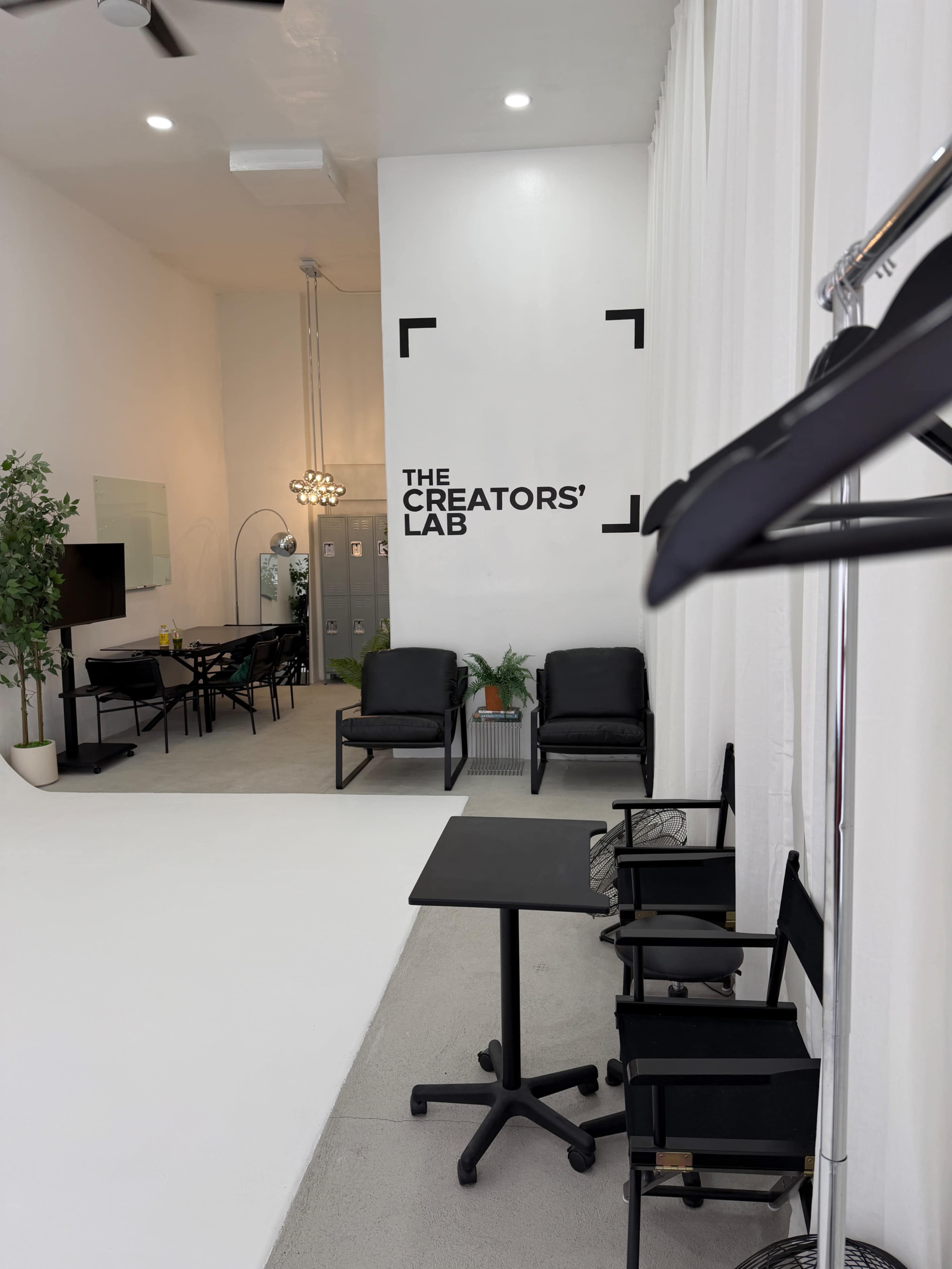 The image shows a modern studio space titled "THE CREATORS' LAB," featuring black seating, a table, and a sleek design with lighting fixtures in the background.
