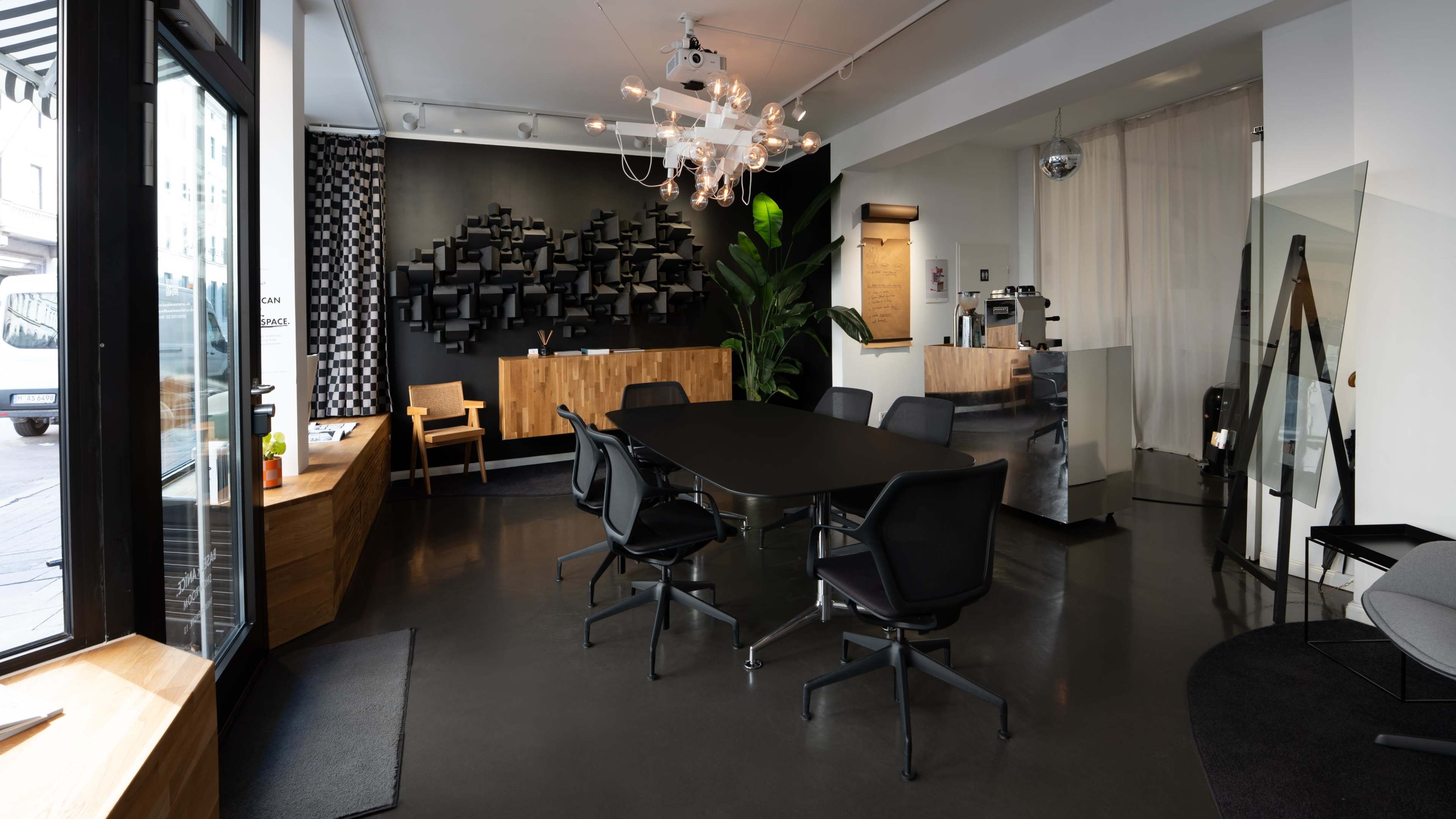 The image shows a modern office space with a large conference table, ergonomic chairs, a reception area with a wooden desk, and large windows allowing natural light.