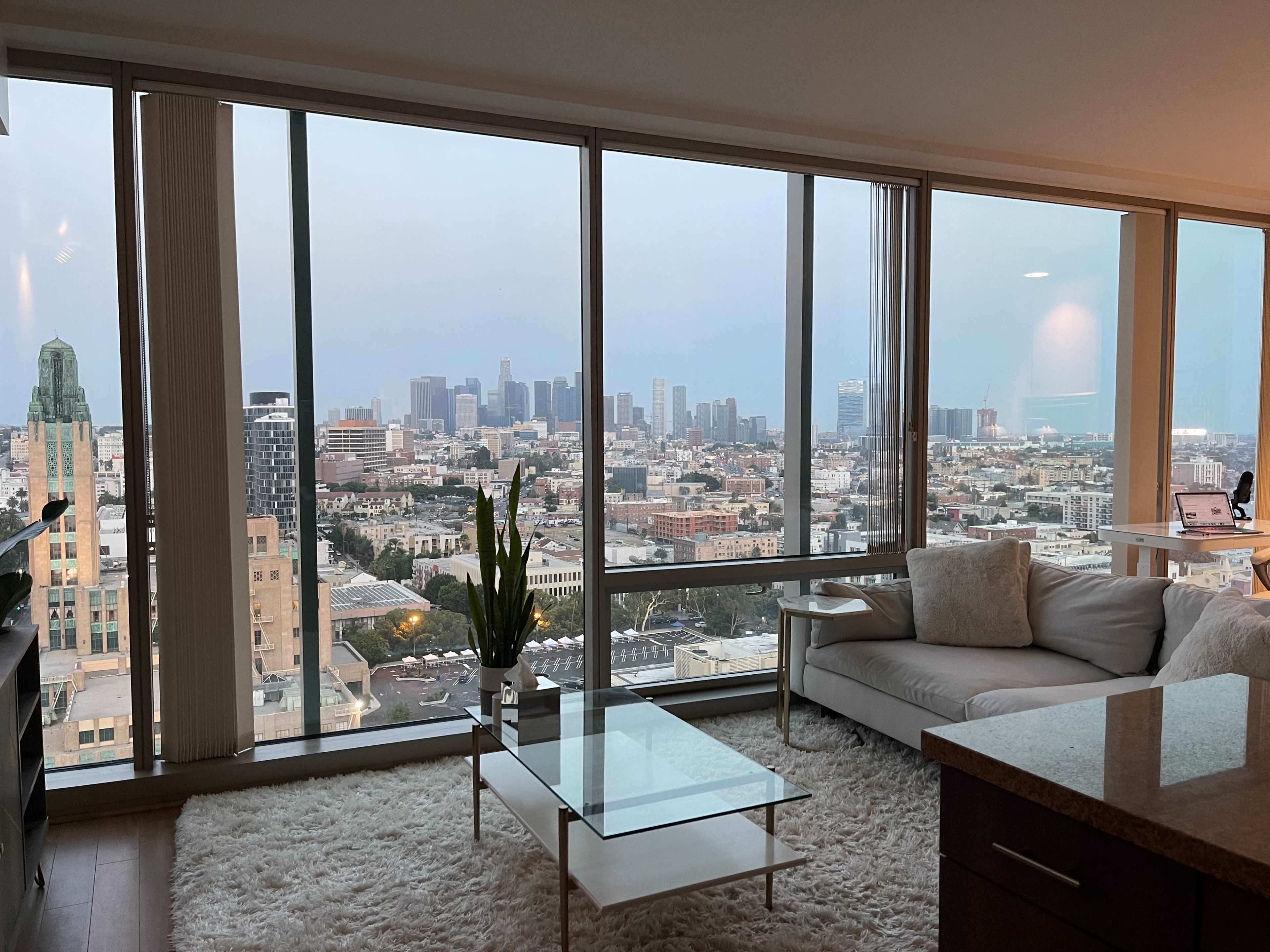 A modern apartment living room with large windows overlooking a city skyline.