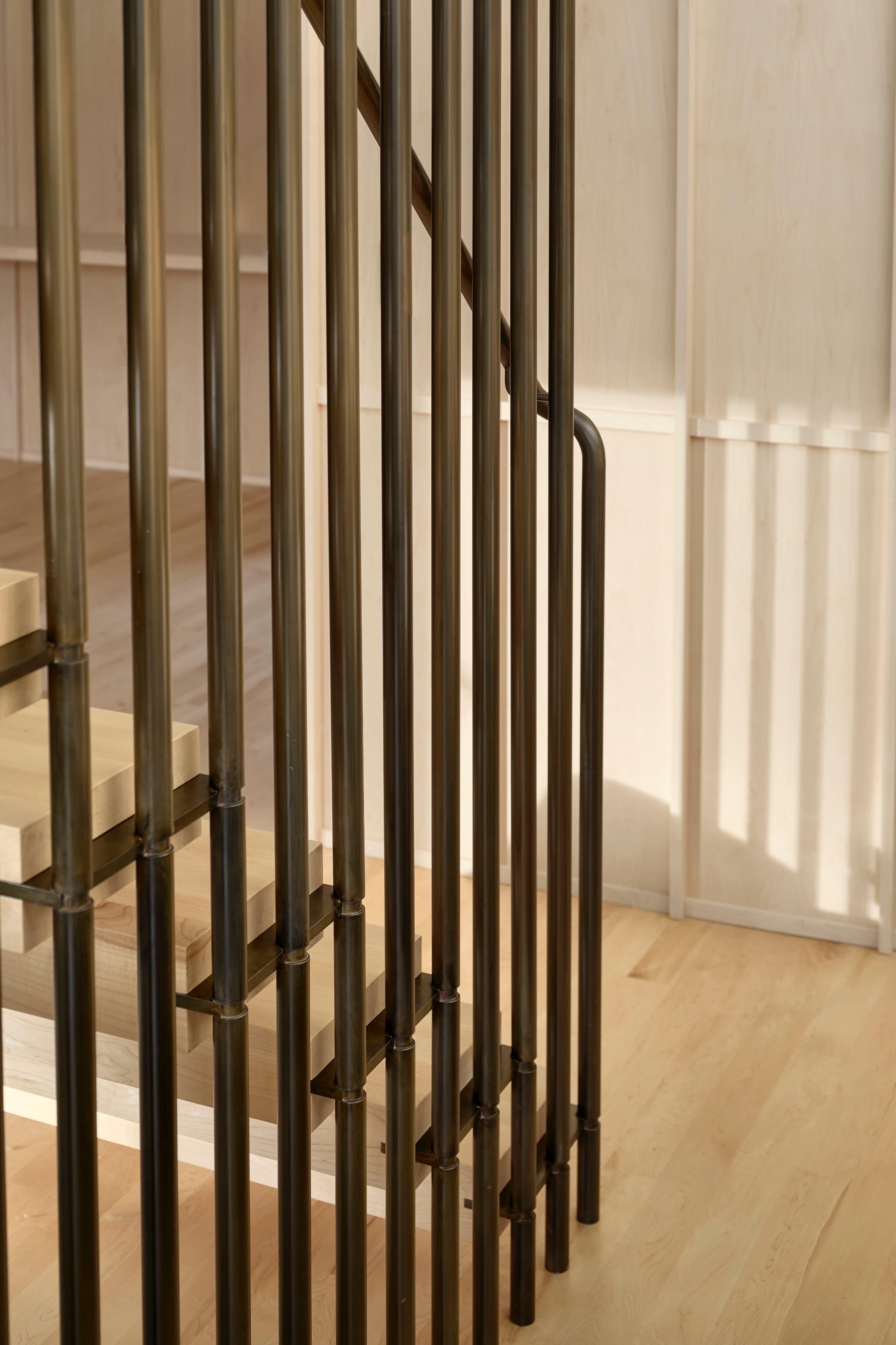 A staircase with metal railings and wooden steps, illuminated by natural light.