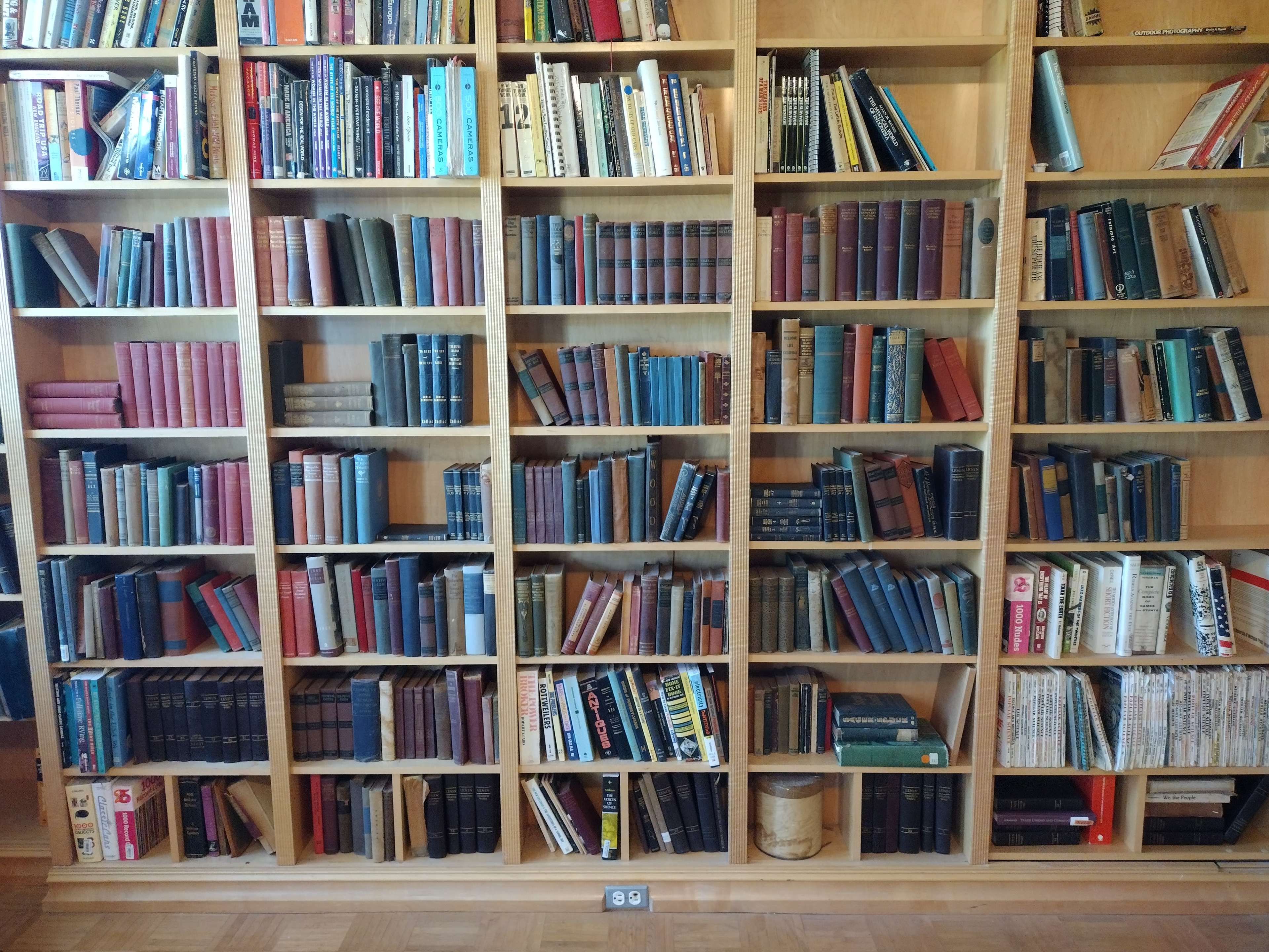 A wooden bookshelf filled with a variety of books, arranged in rows and displaying a mix of colors and sizes.