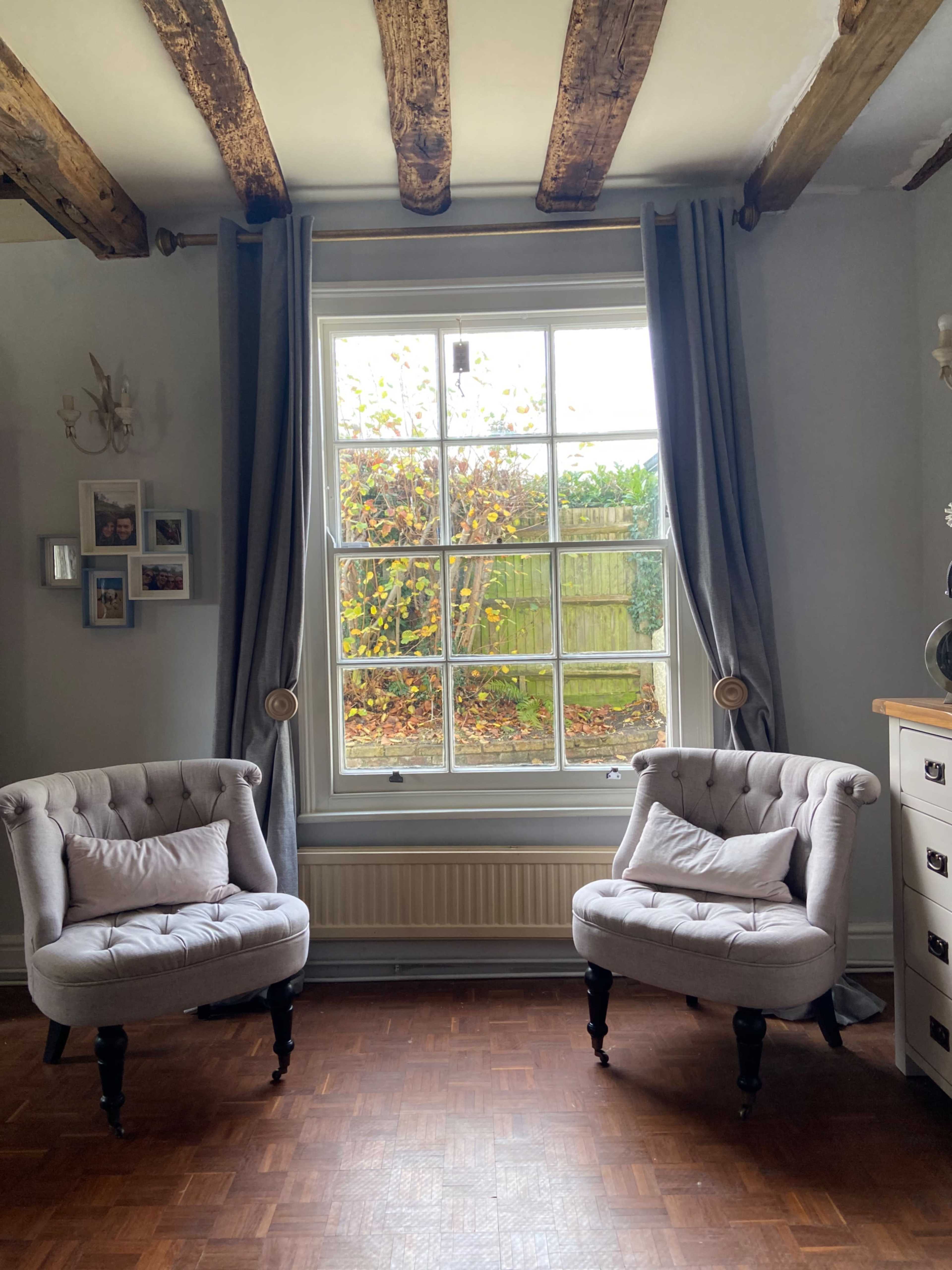 Two tufted armchairs positioned in a room with a large window overlooking a garden.