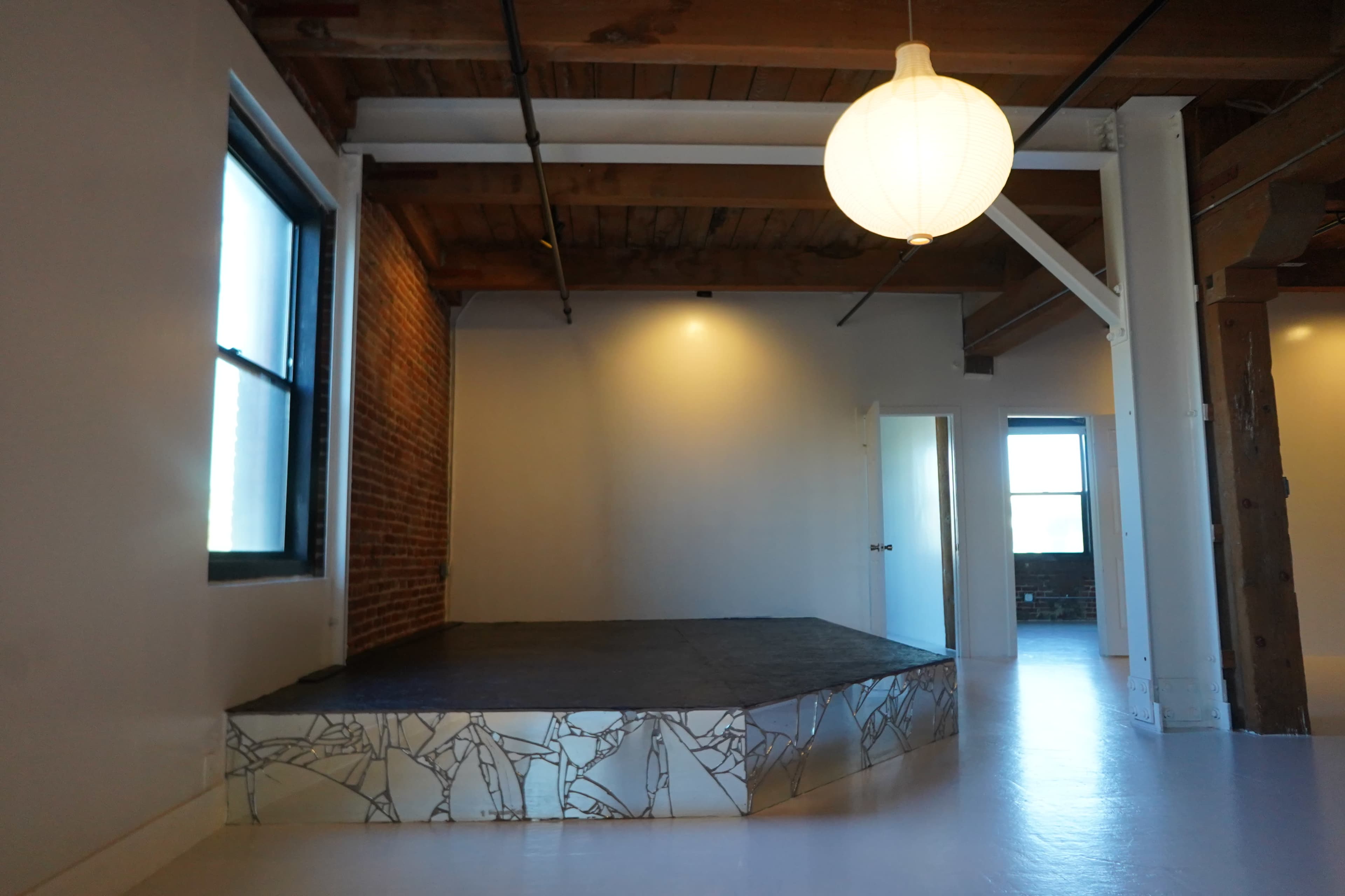 The scene features a spacious interior with a raised stage area and a large pendant light hanging from the ceiling.