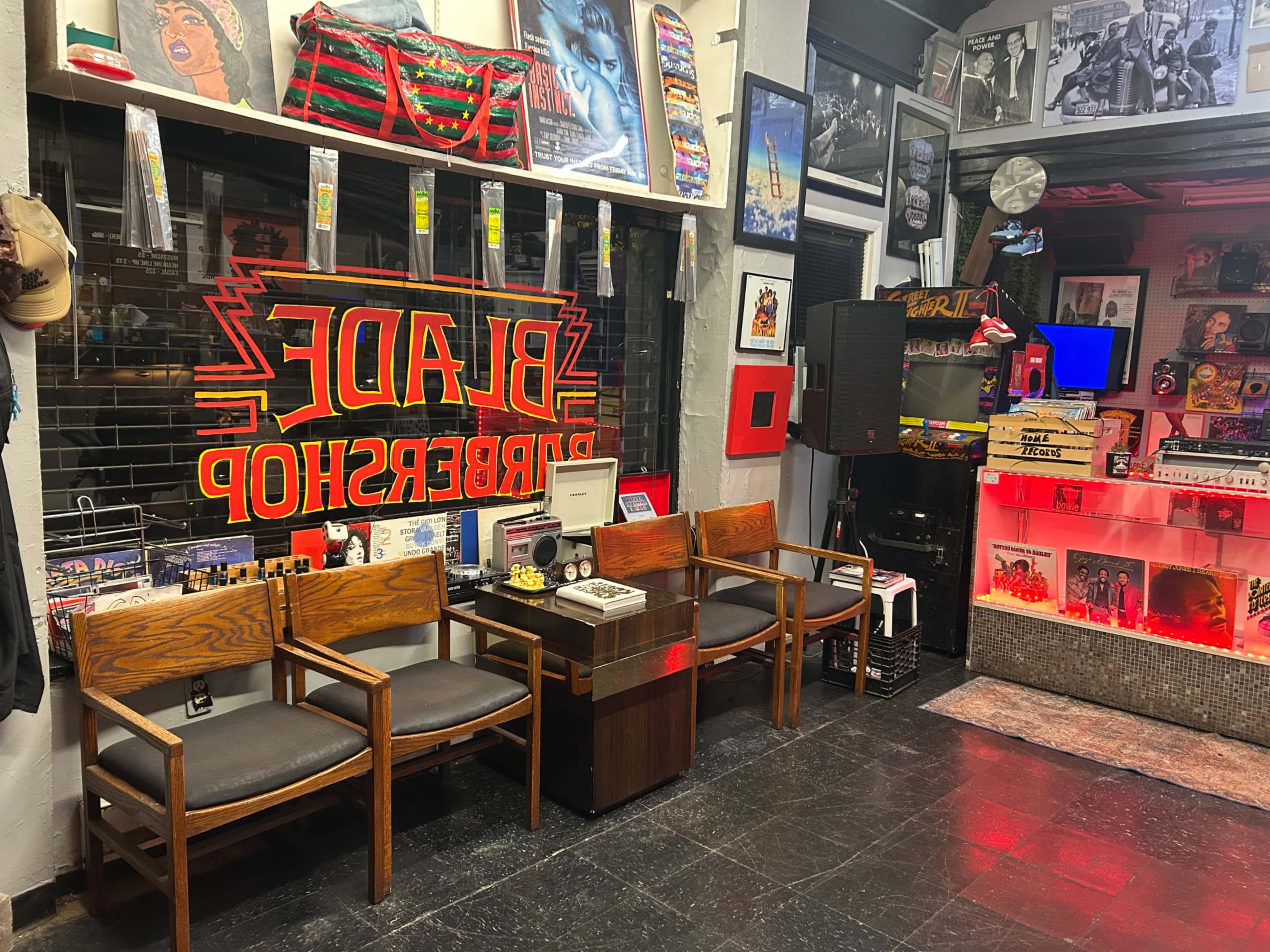 The image depicts the interior of a barbershop featuring wooden chairs, artwork on the walls, and a brightly lit display area with various items.