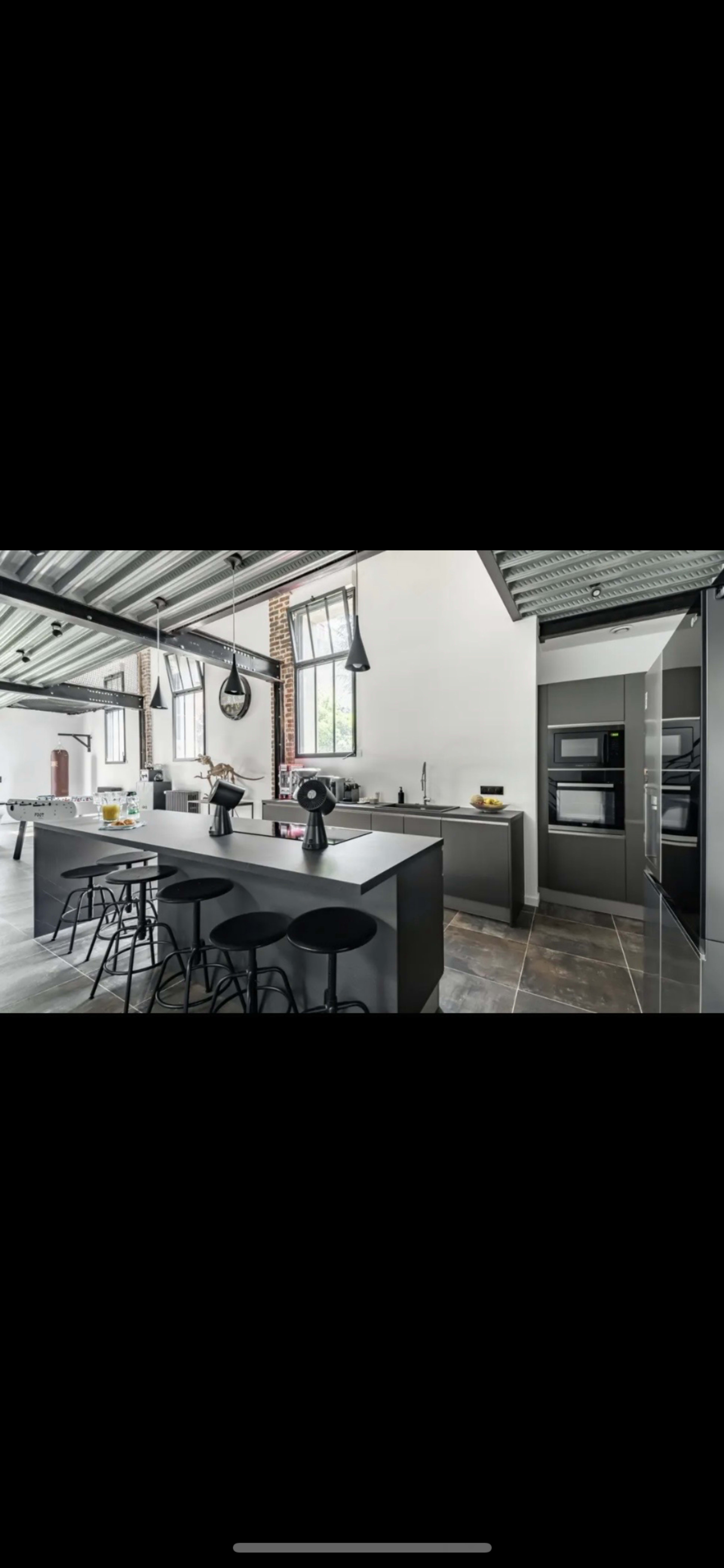 A modern kitchen with a large central island, sleek cabinetry, and industrial-style lighting fixtures.