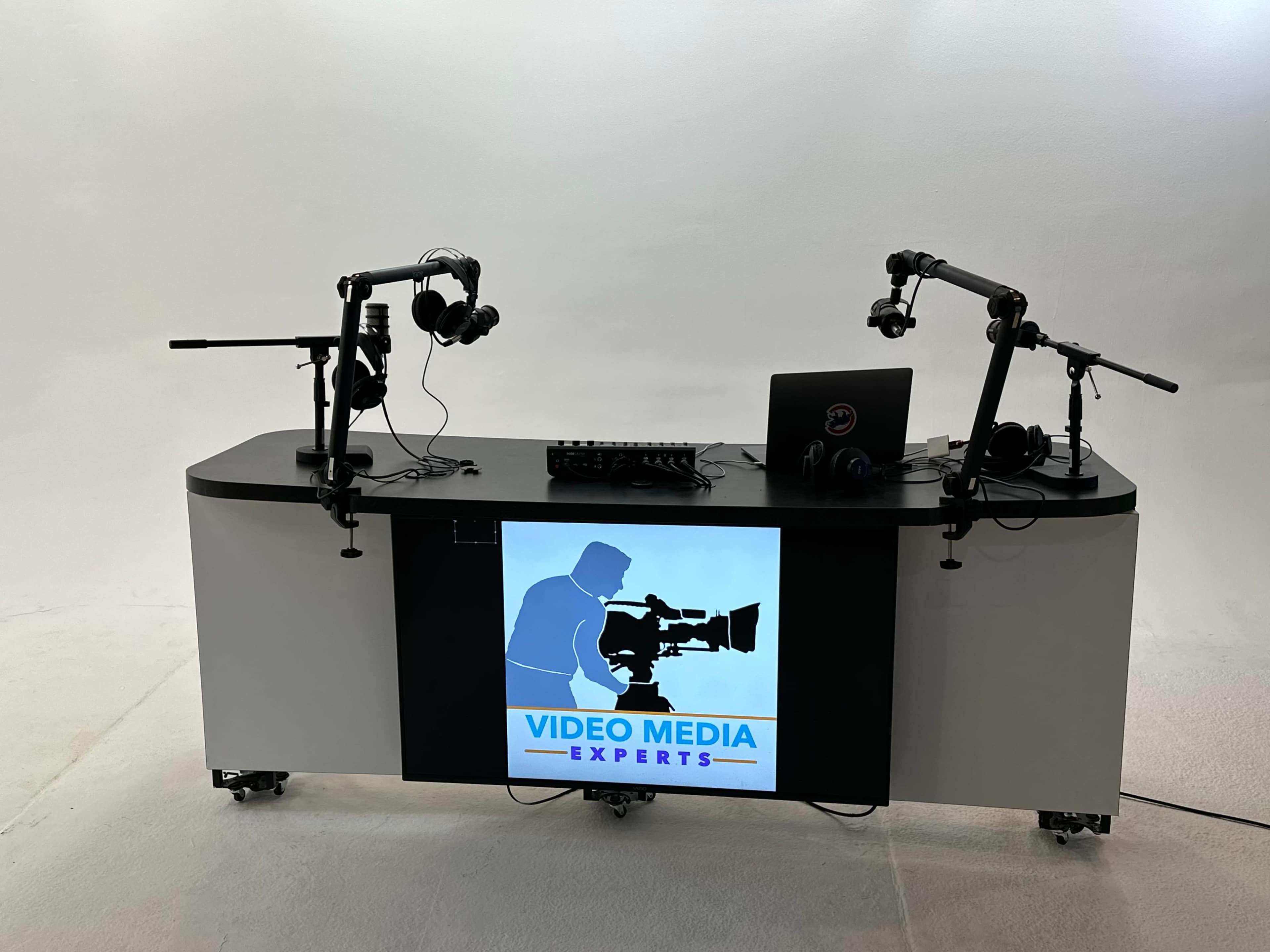 A video media studio setup features a table with headphones, a laptop, and equipment for video recording.