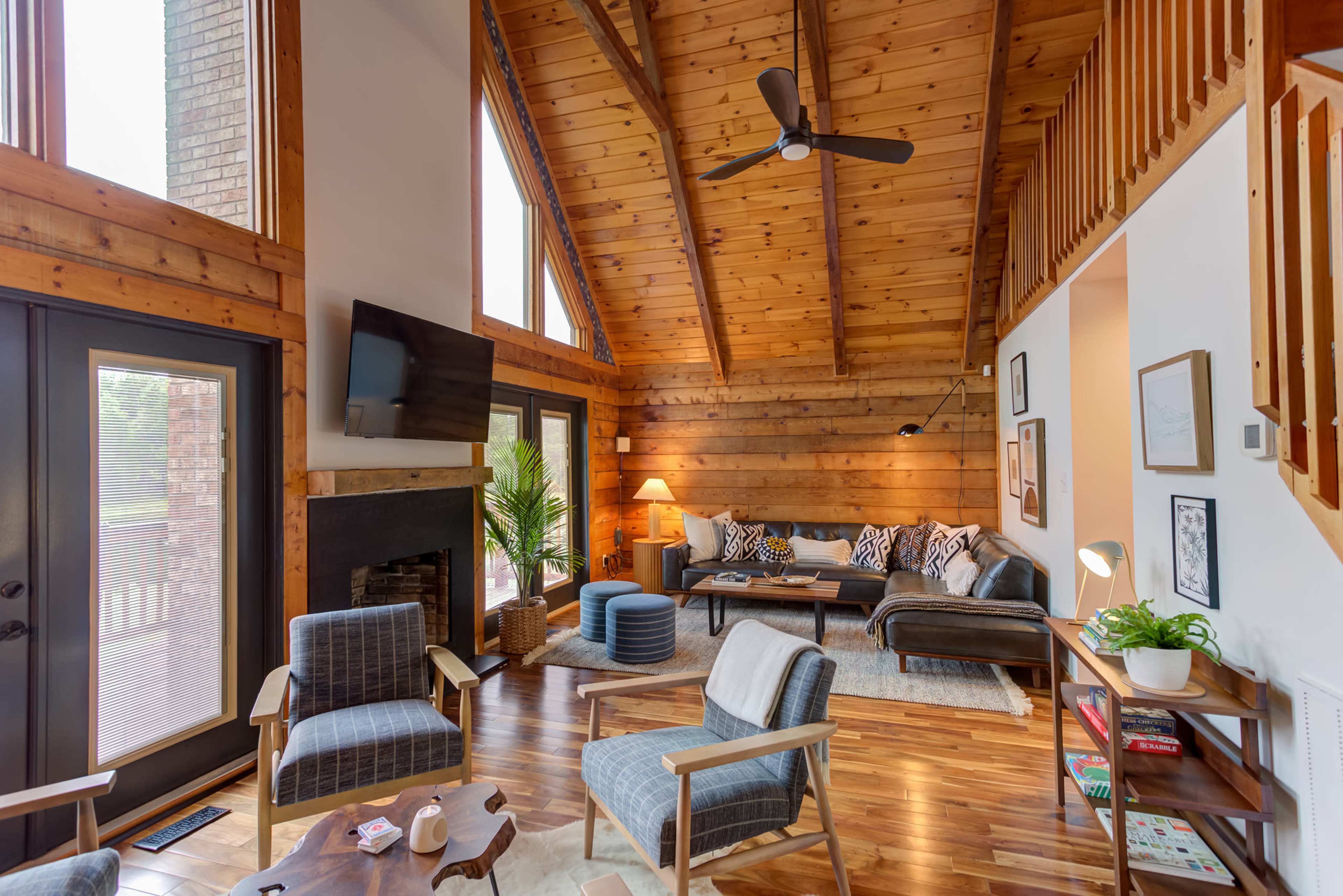A cozy living room with wooden beam ceilings, a fireplace, and a combination of modern and rustic furniture.