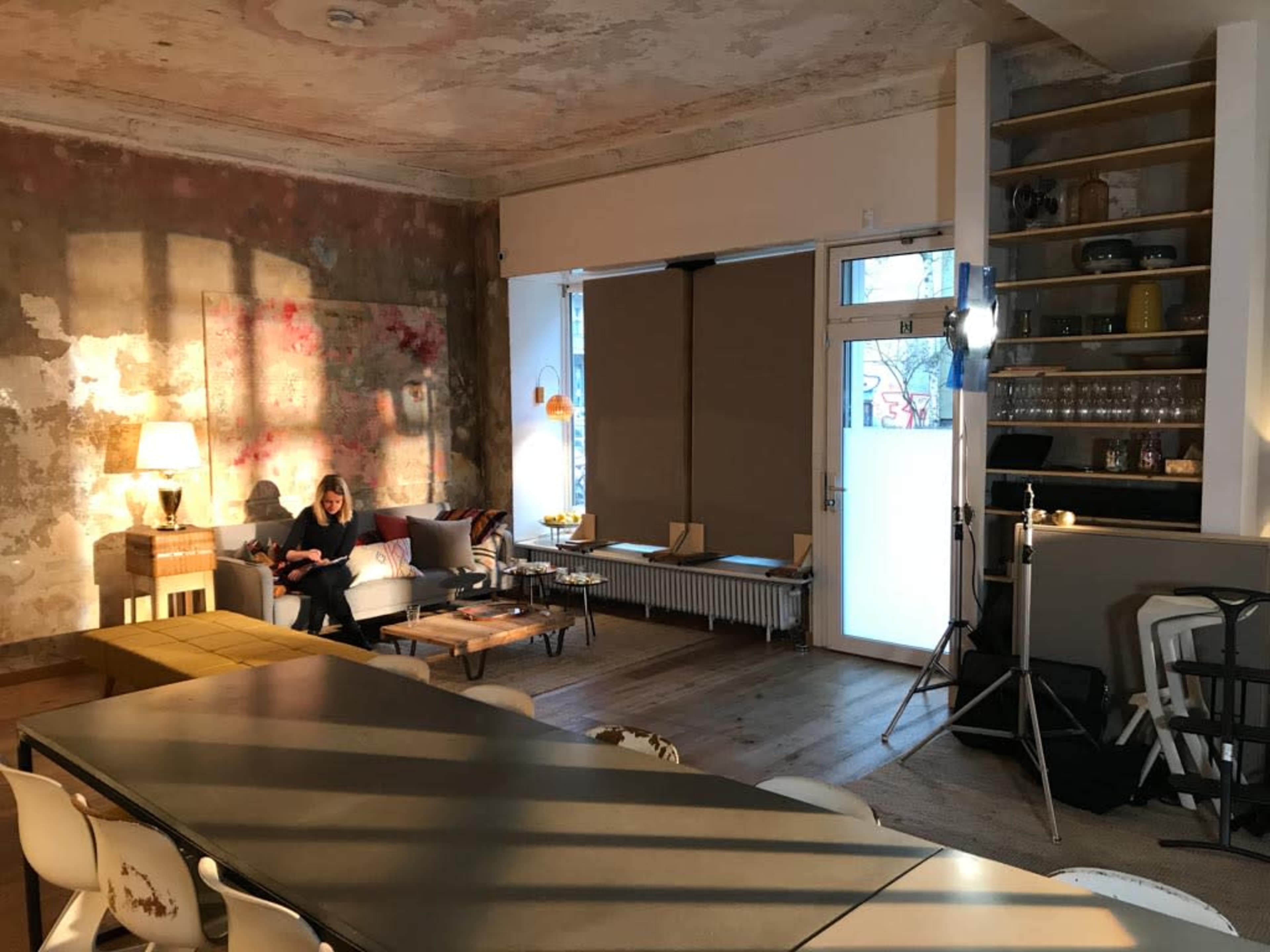 The scene features a spacious, partially unfinished room with a mix of modern furniture and a cozy seating area.