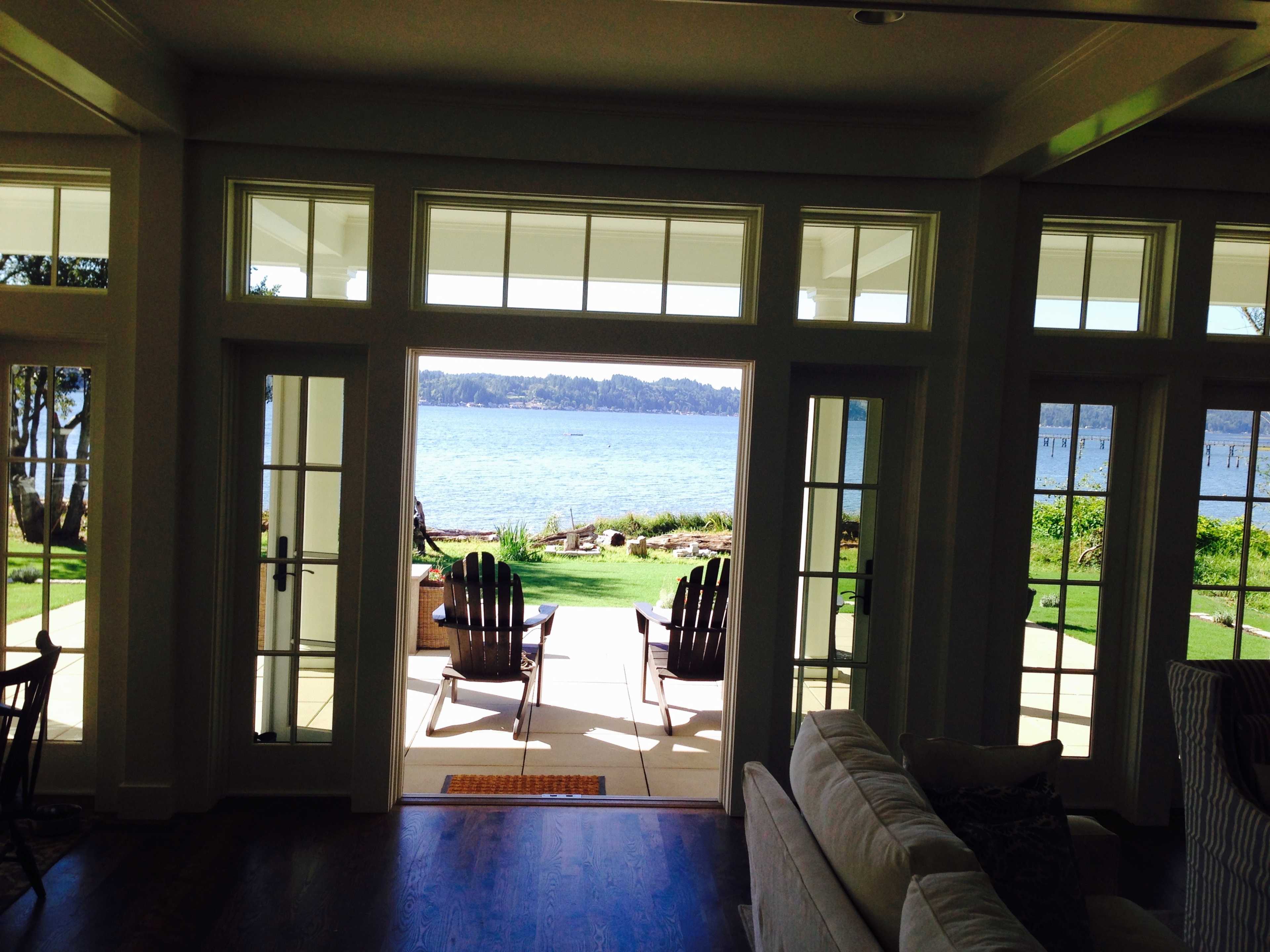 A view from inside a house looking out through large glass doors onto a patio that overlooks a body of water.