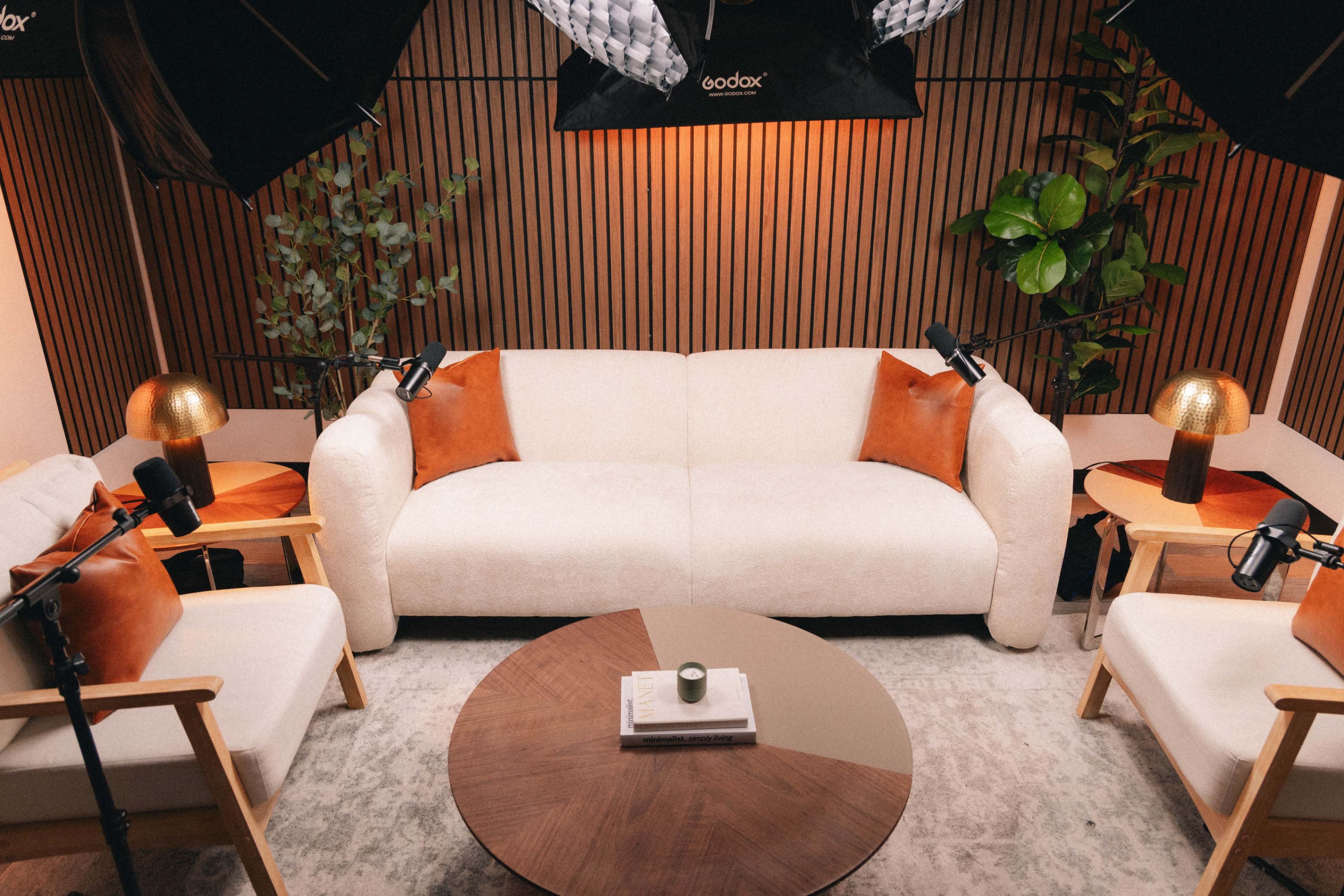 The scene shows a modern living room setup with a light-colored sofa, accent pillows, two wooden side tables, a round coffee table, and various indoor plants, all under soft lighting.