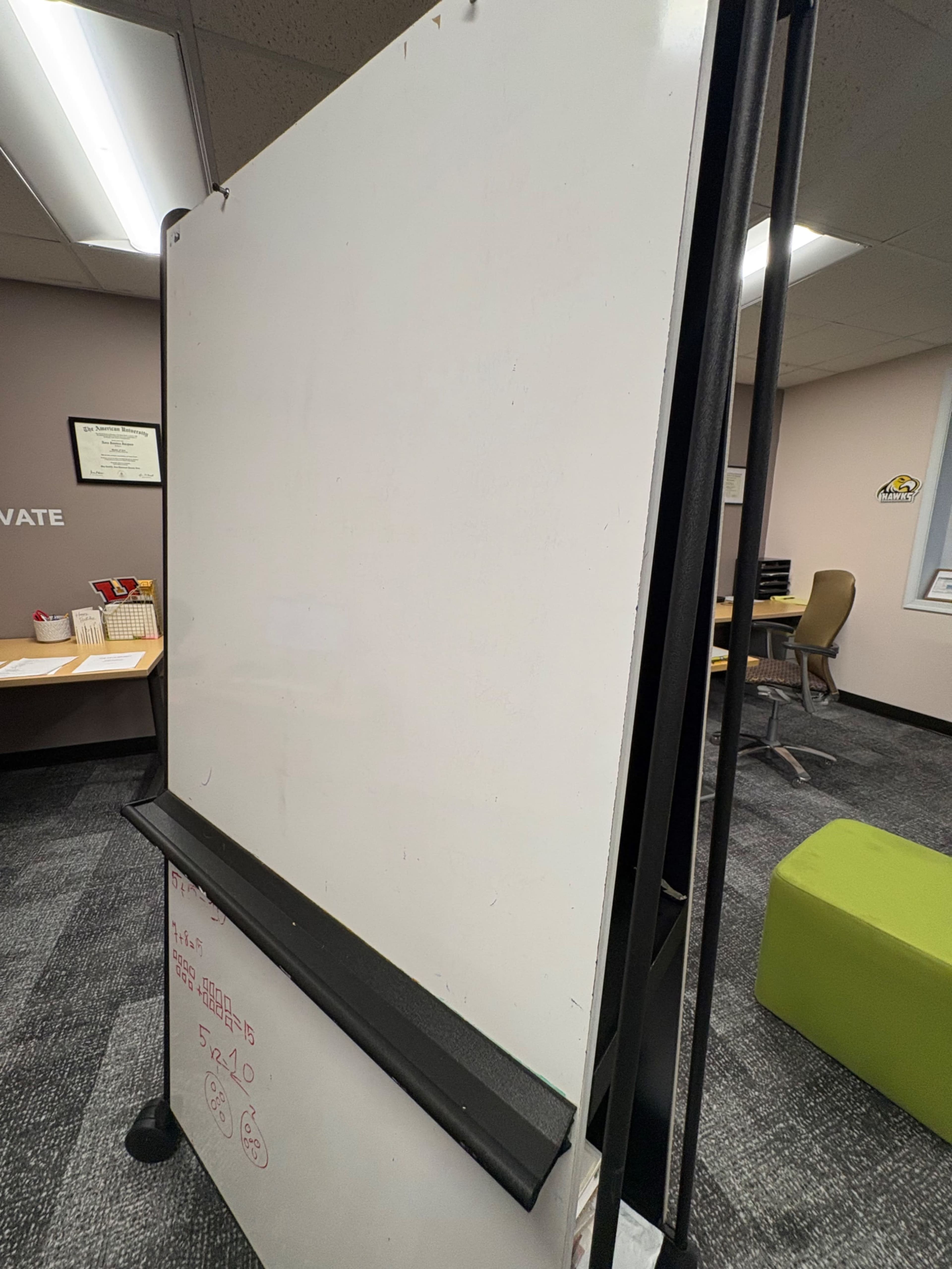 The image shows a blank whiteboard on a portable stand in an office setting.