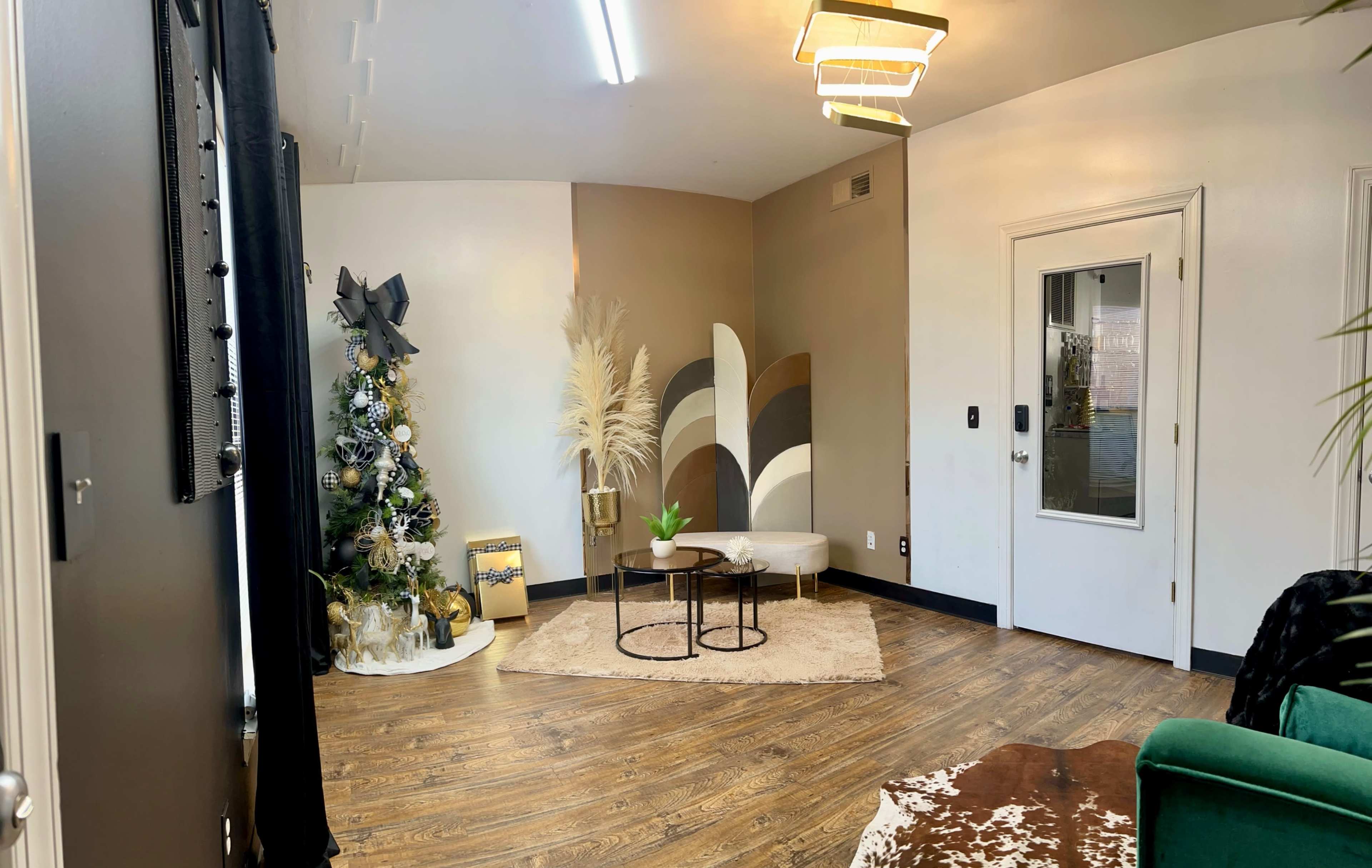 The room features a holiday-themed corner with a decorated Christmas tree, a circular seating arrangement, and a mix of neutral wall colors.