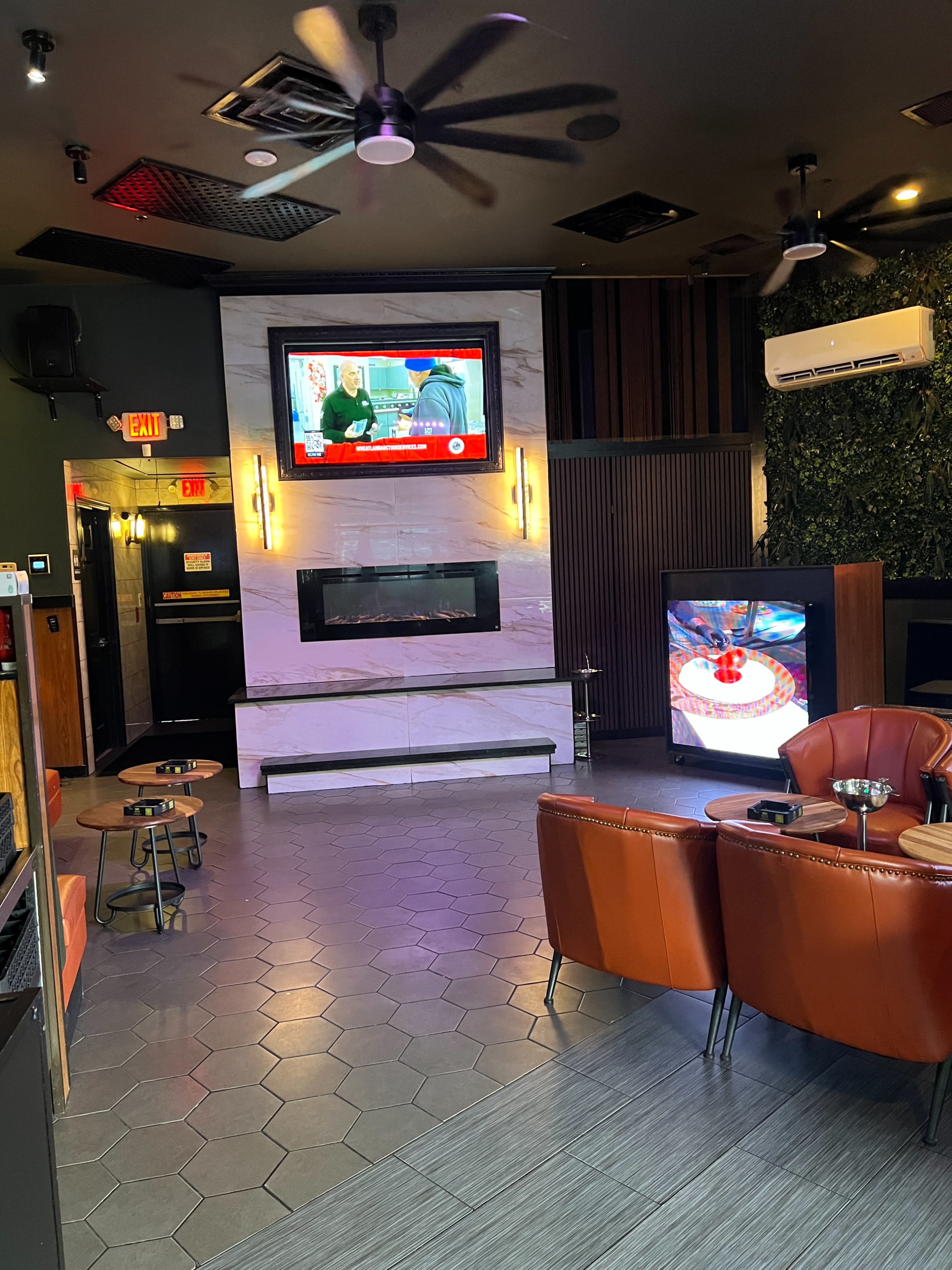 The image shows a modern lounge area with a television mounted on the wall, a fireplace, and seating arranged around a coffee table.