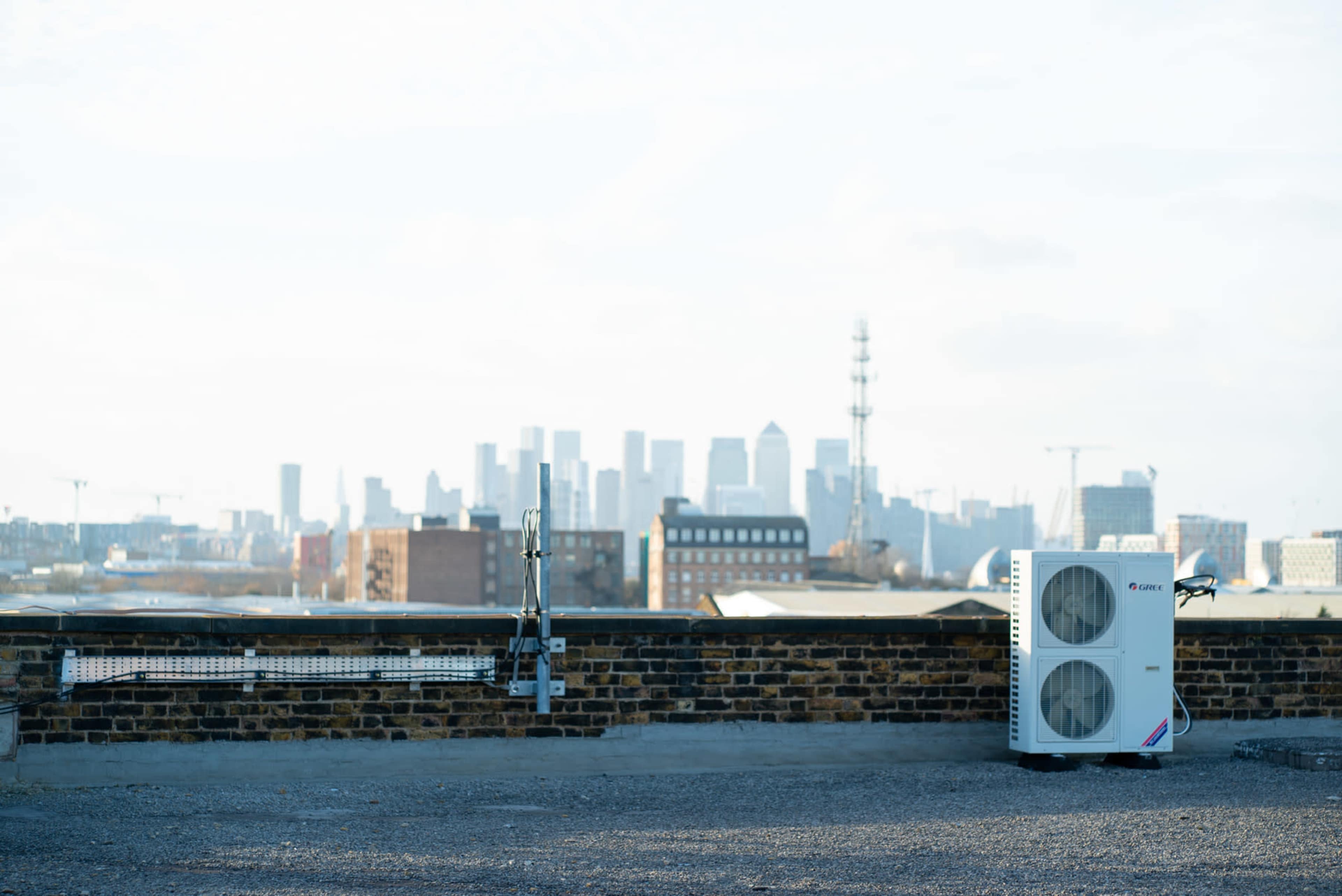 A rooftop with an air conditioning unit on one side and a view of a city skyline in the background.