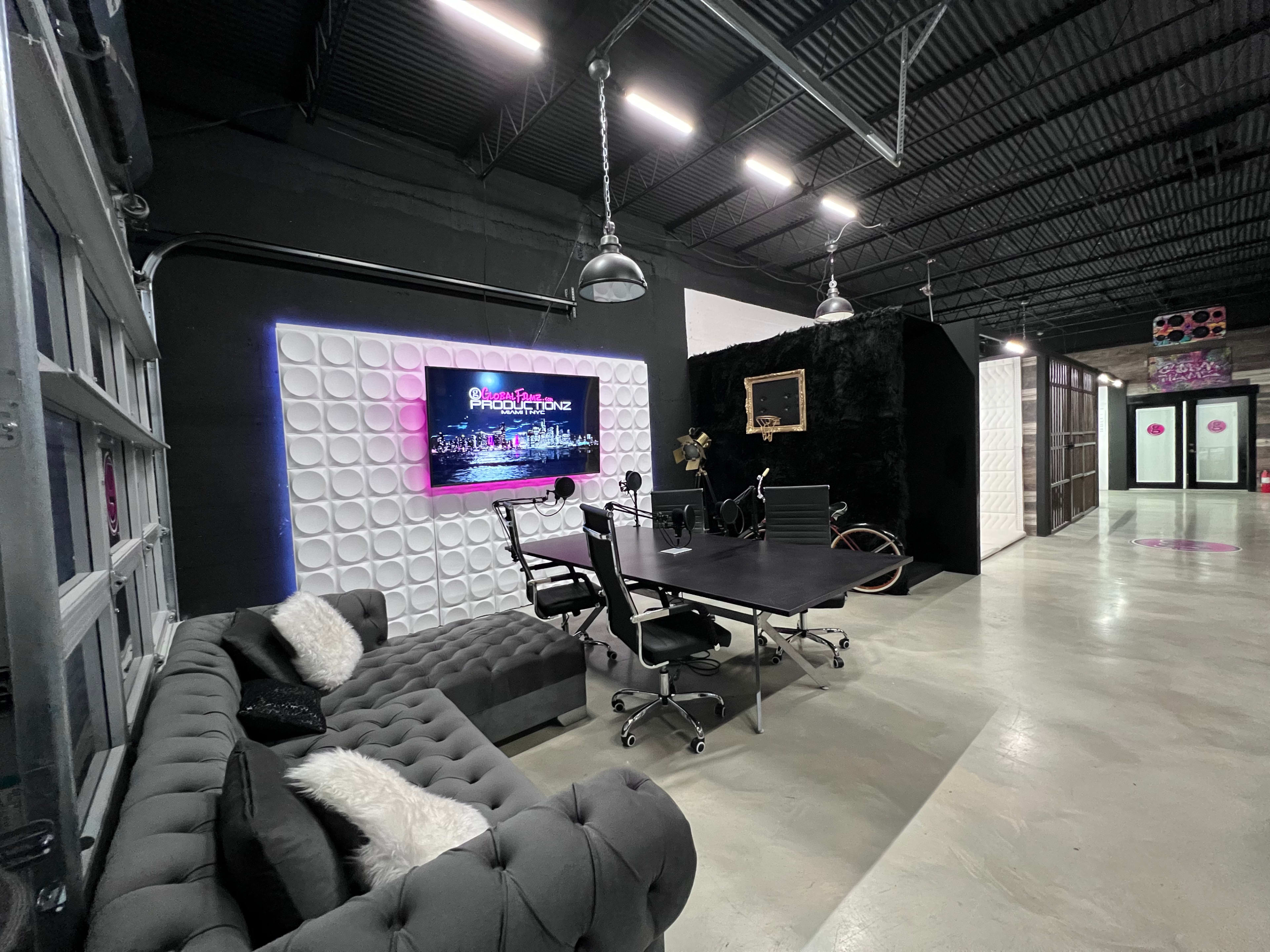 The image shows a modern office space featuring a conference table with chairs, decorative wall elements, and a bike against a black partition.