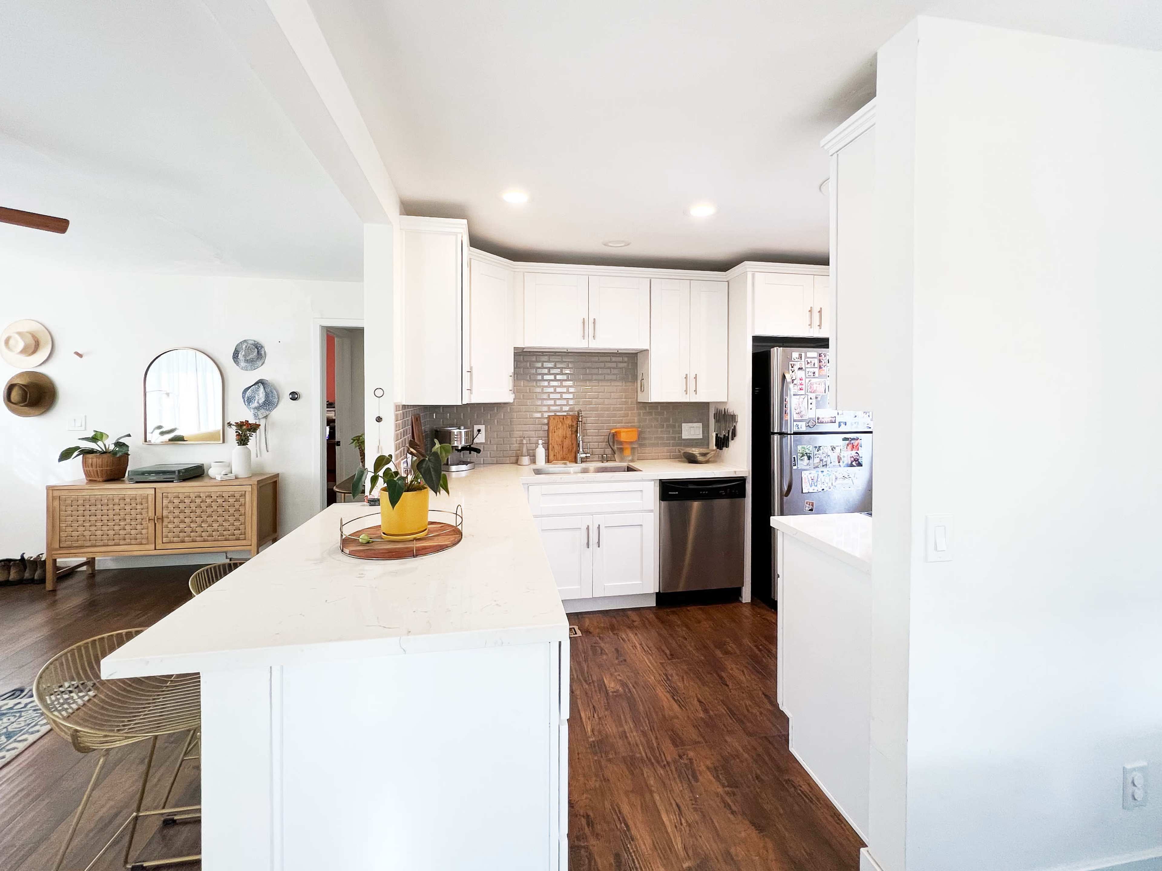 A modern kitchen with white cabinetry, stainless steel appliances, and a central island featuring a small plant.