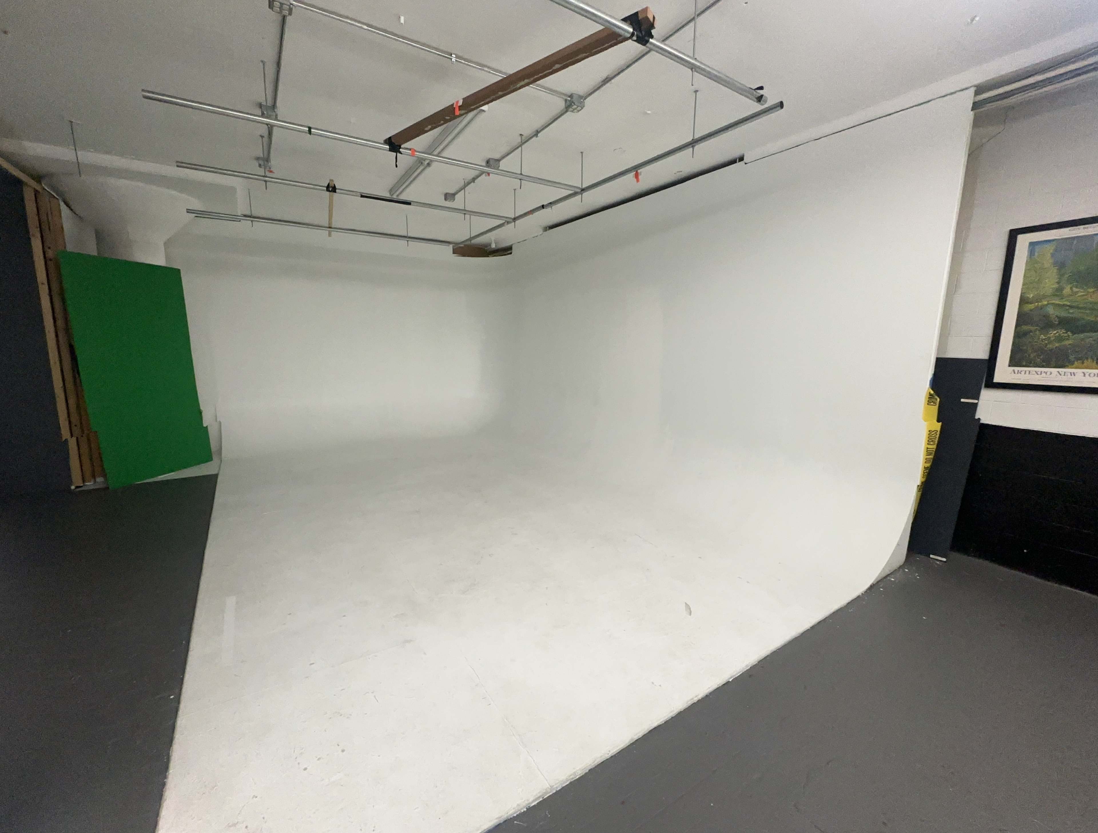 A blank studio space with a curved, white backdrop, green screen on the left, and a gray floor.
