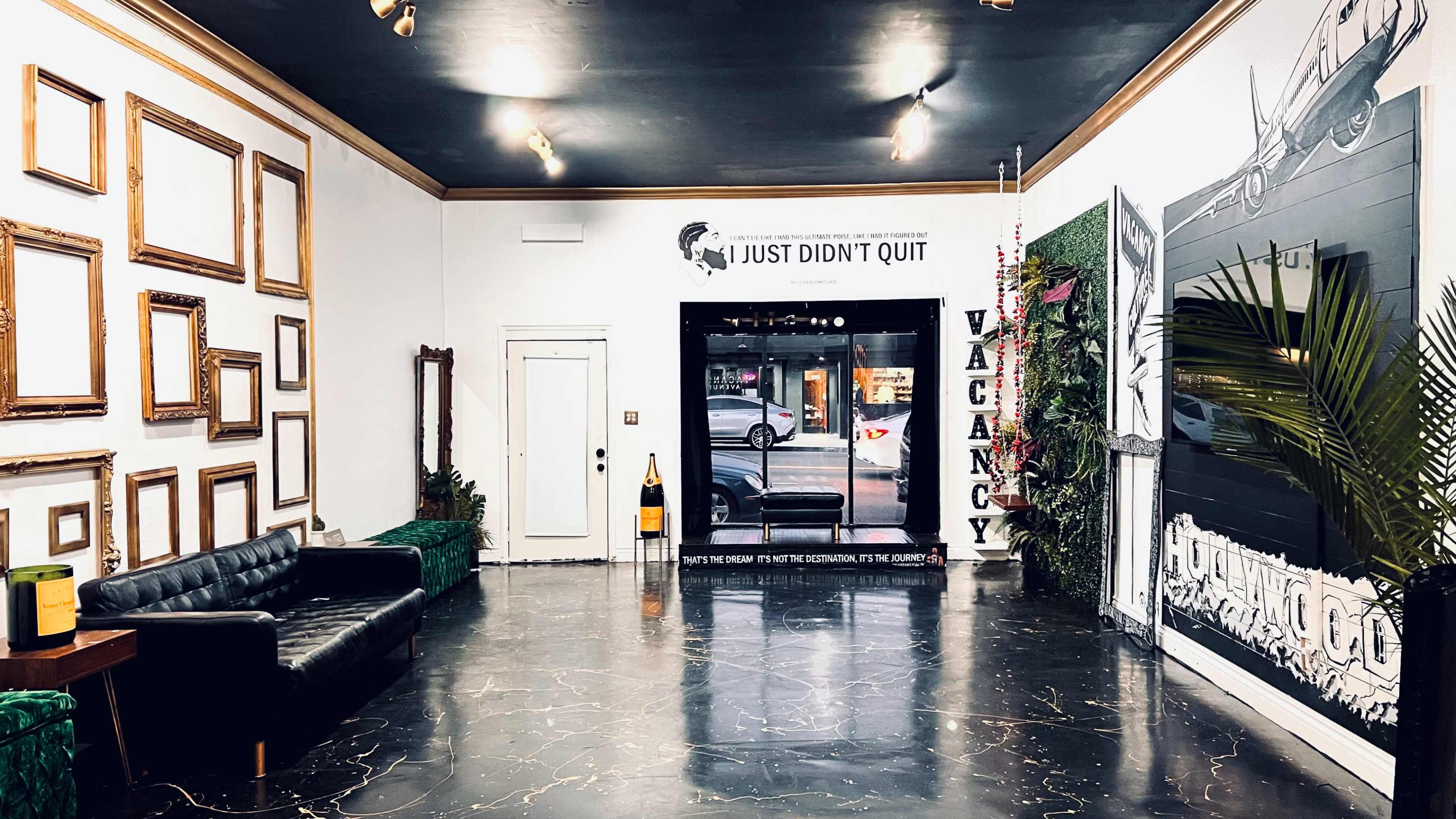 The scene features a lobby area with a black sofa, vacant sign, and empty picture frames on the walls.