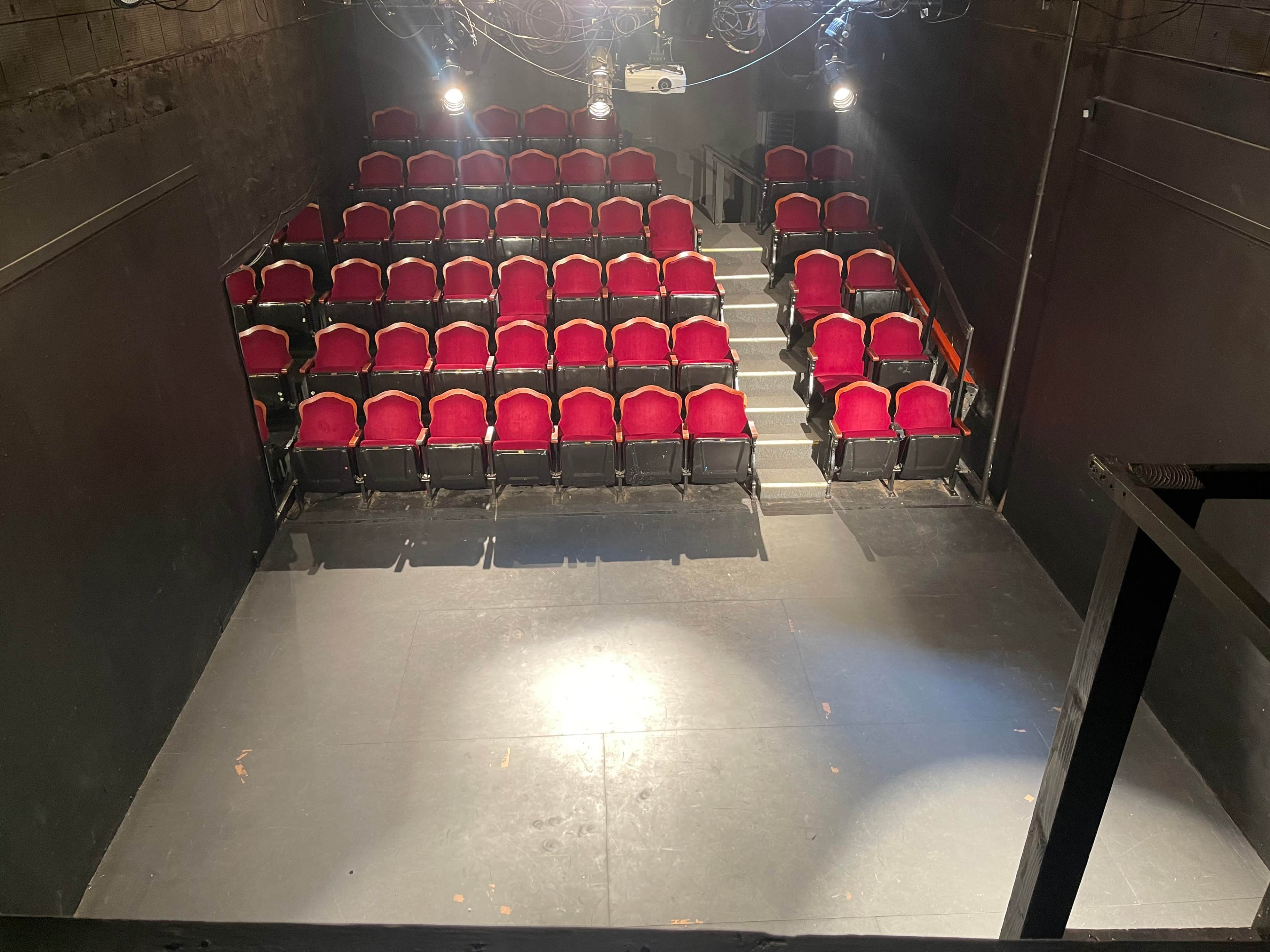 A small theater with red upholstered seats arranged in rows facing a stage area.