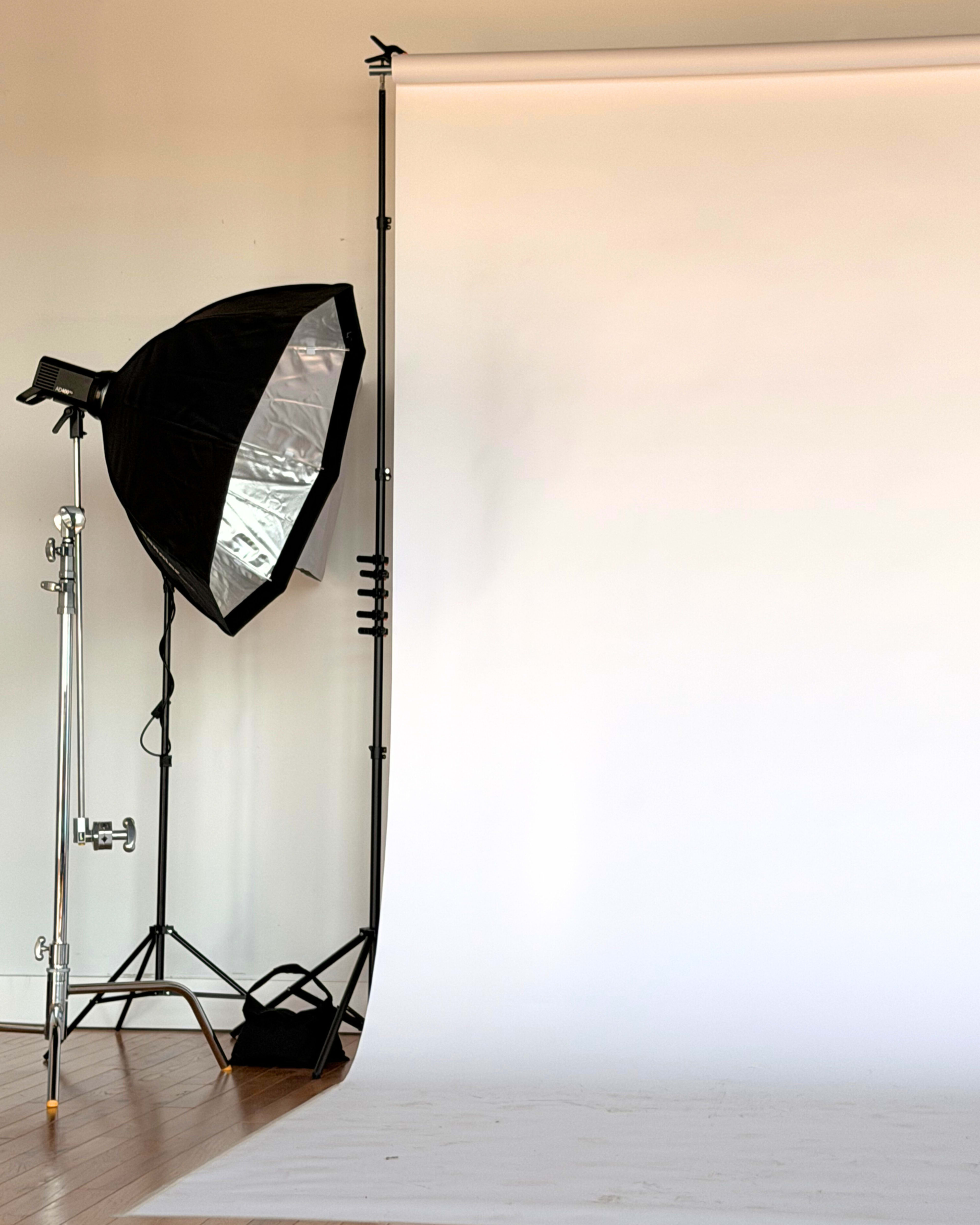 A photography studio setup featuring a large softbox light and a seamless white backdrop.