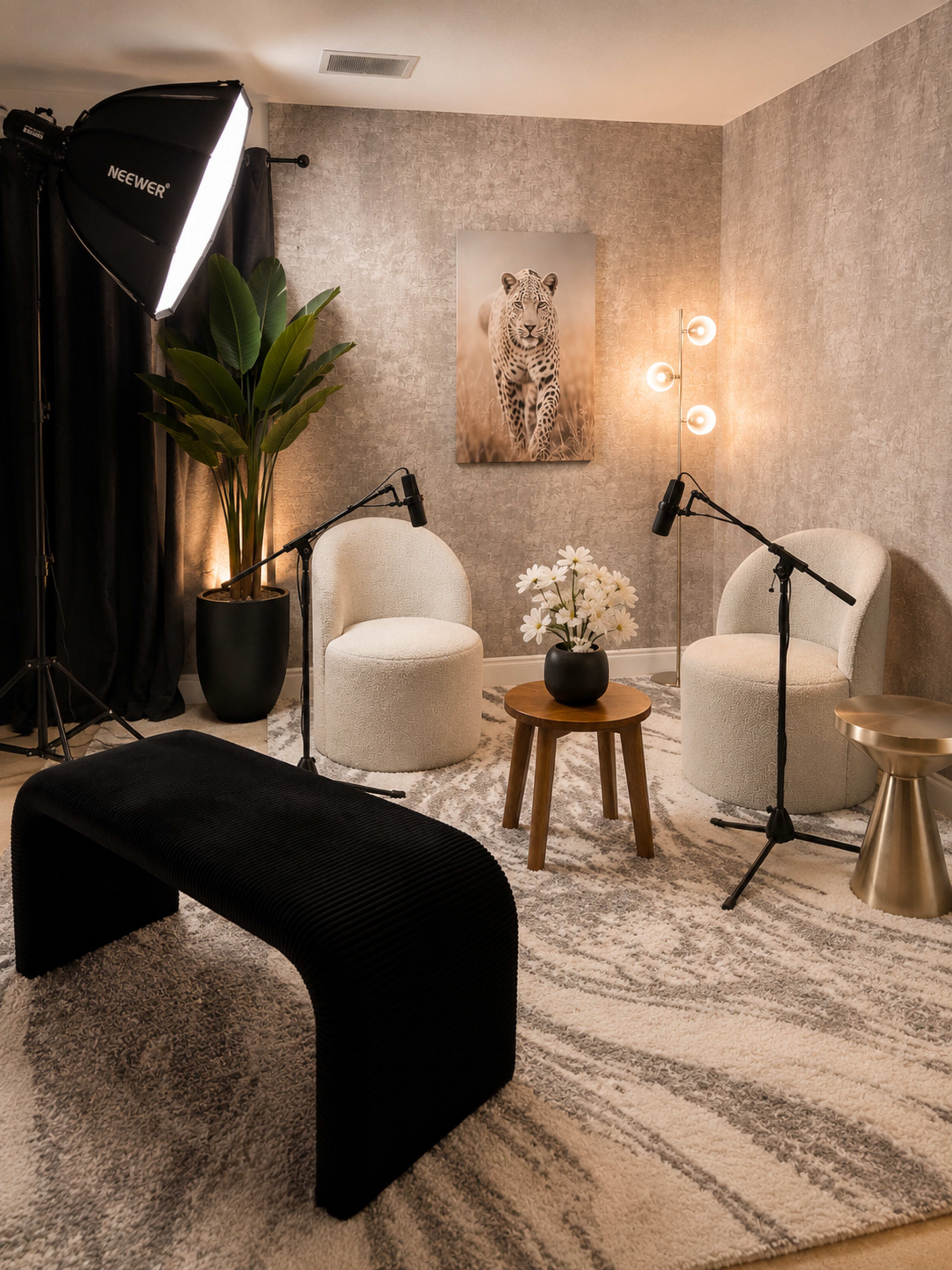 The image shows a cozy interview setup with two upholstered chairs, a small circular table, and a backdrop featuring a lion portrait, illuminated by decorative lighting.