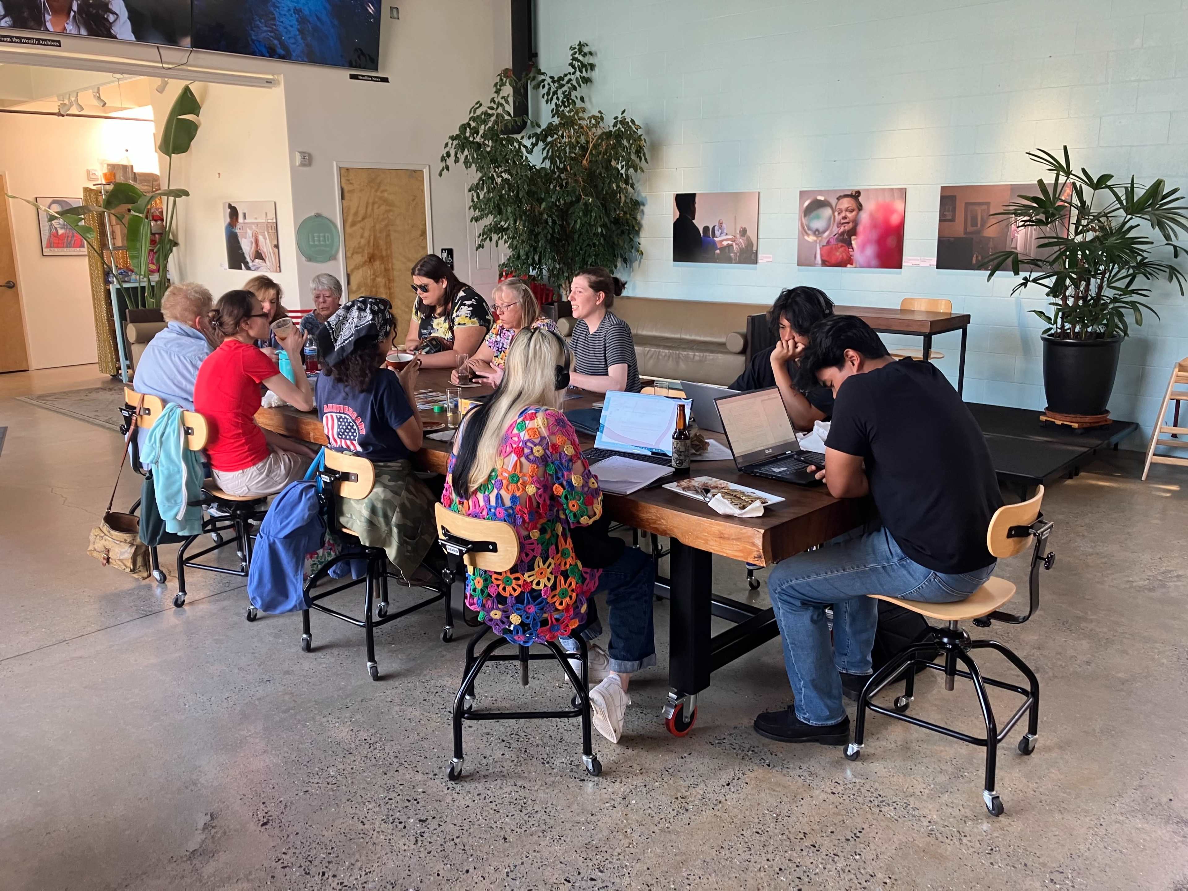 A diverse group of individuals collaborates around a large table in a modern workspace.