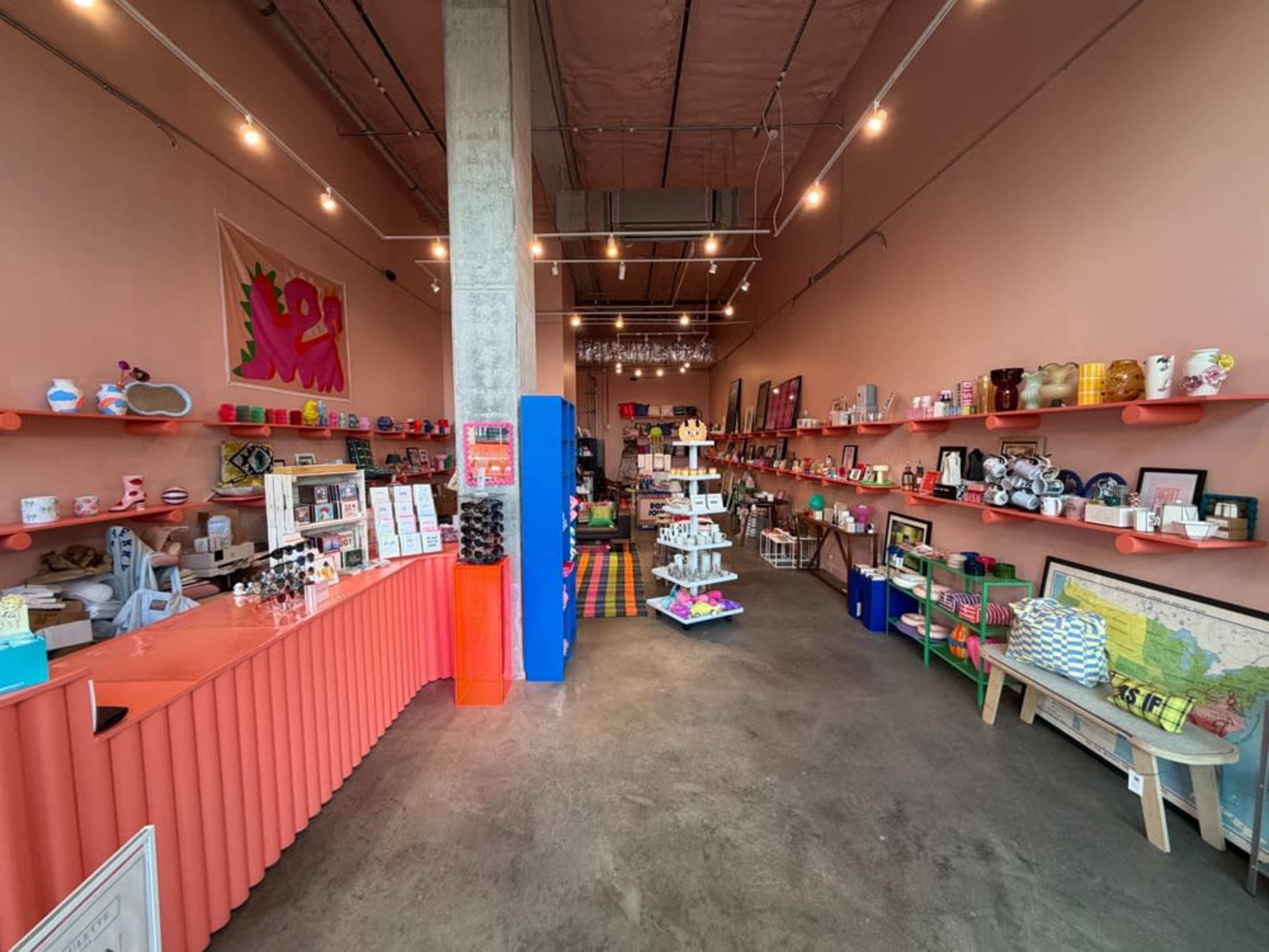 The image shows a colorful retail shop interior with various decorative items arranged on shelves and displays along the walls.