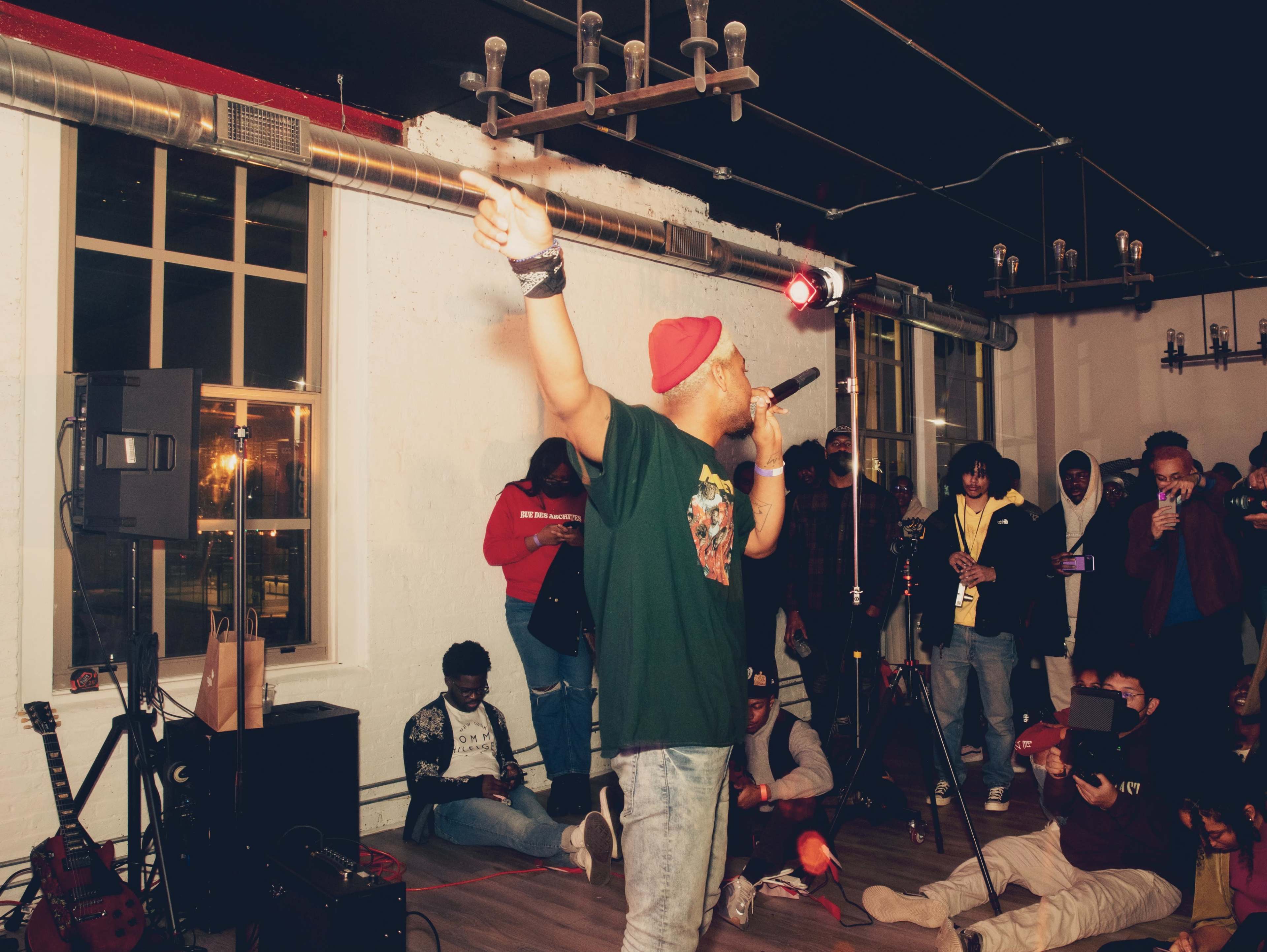 A performer on stage with a microphone captivates an audience in a crowded indoor venue.
