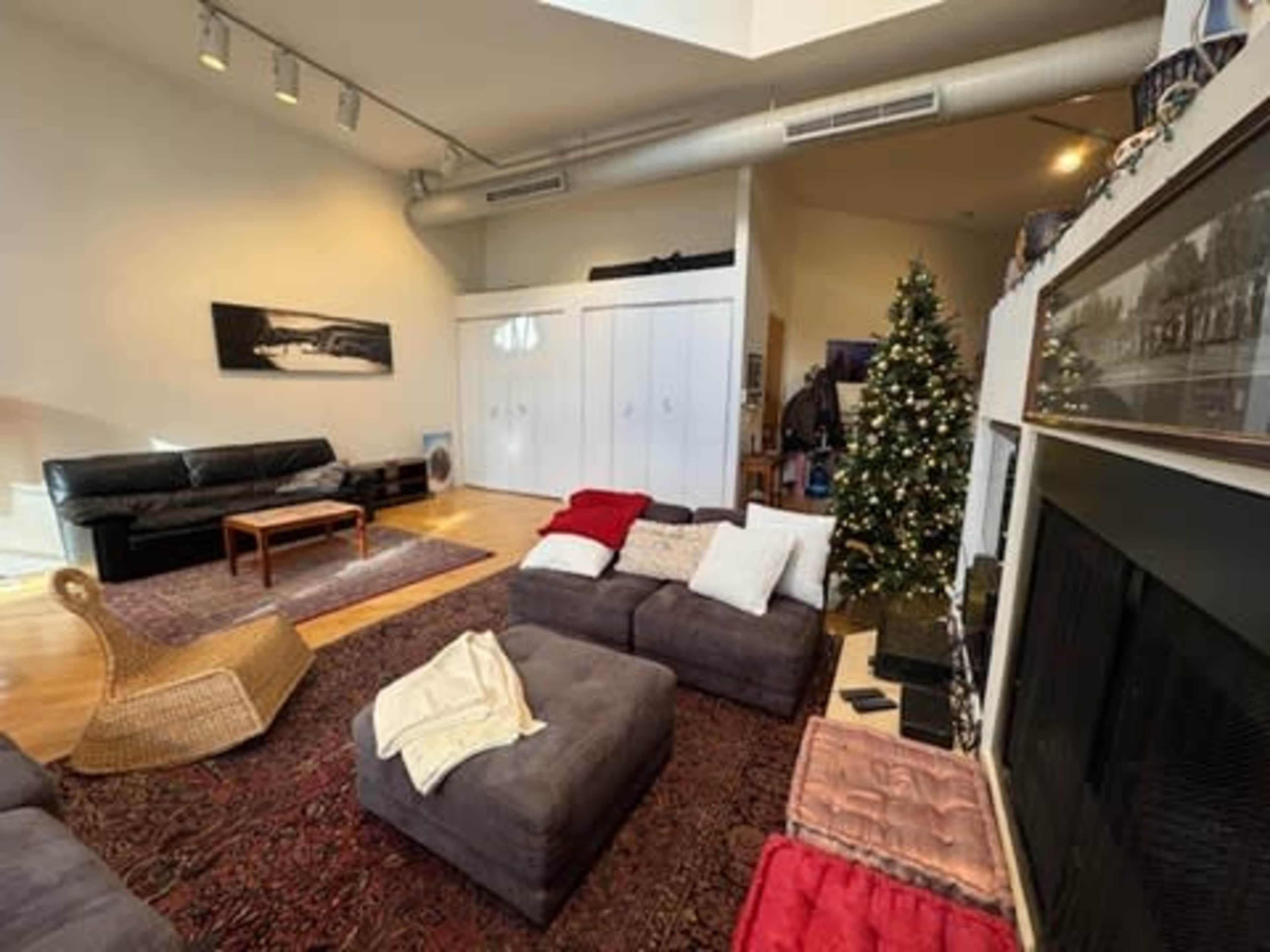 The image shows a spacious living room with a cozy seating arrangement, a Christmas tree, and a fireplace.