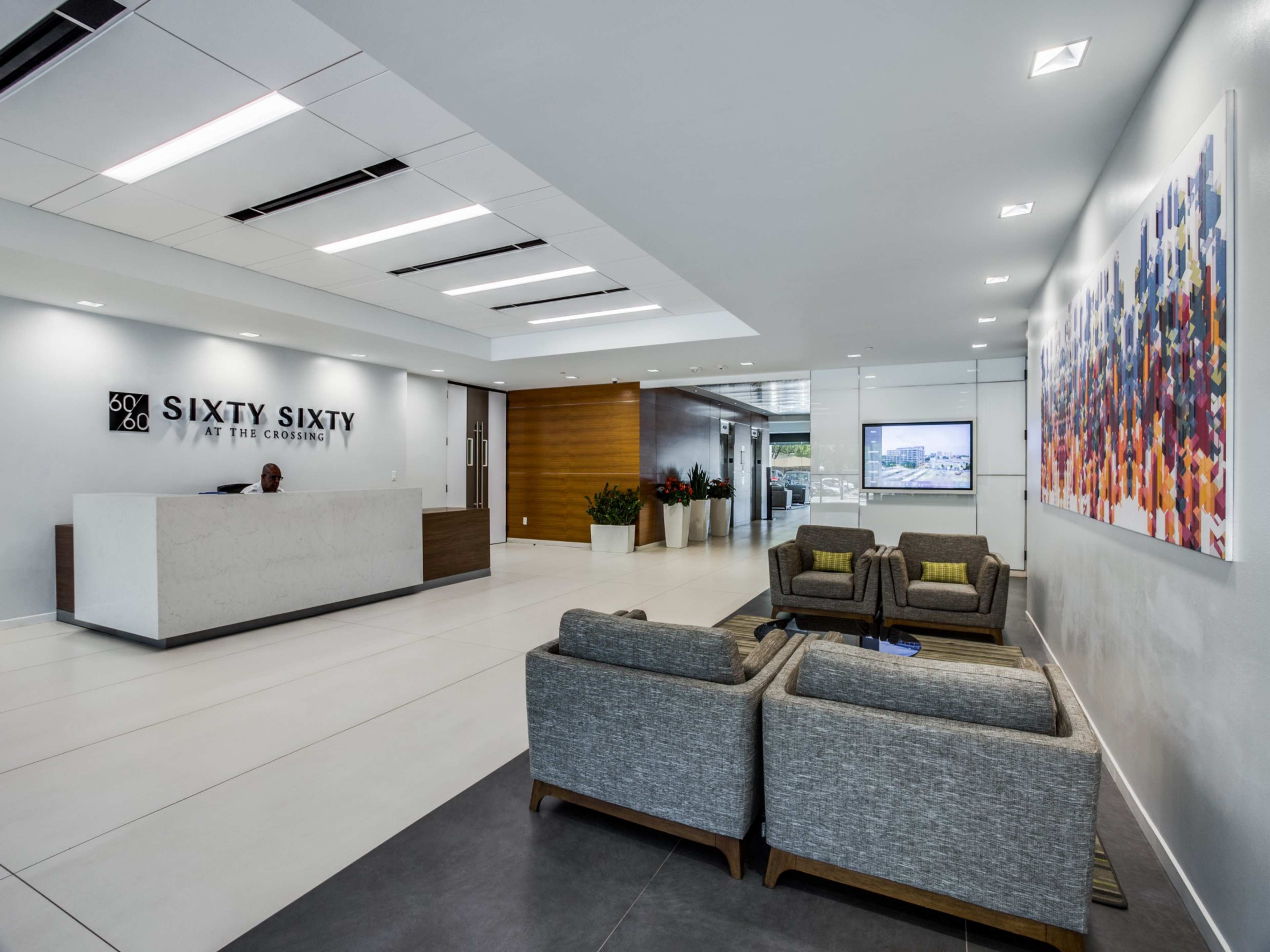 A modern lobby with a reception desk, seating area, and a large artwork on the wall.