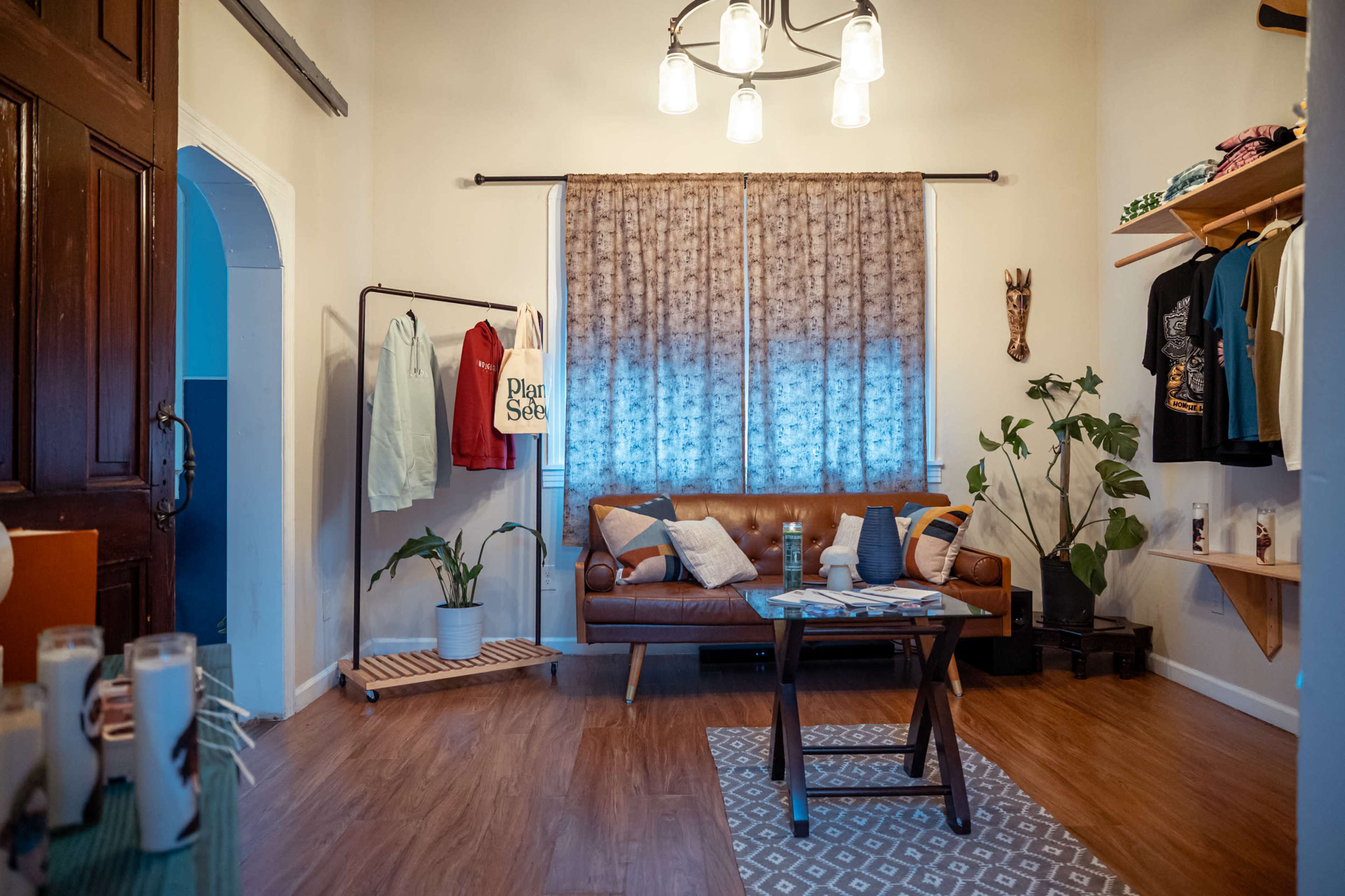 A cozy living space featuring a brown leather sofa, a patterned rug, a small wooden table, and various decorative plants.