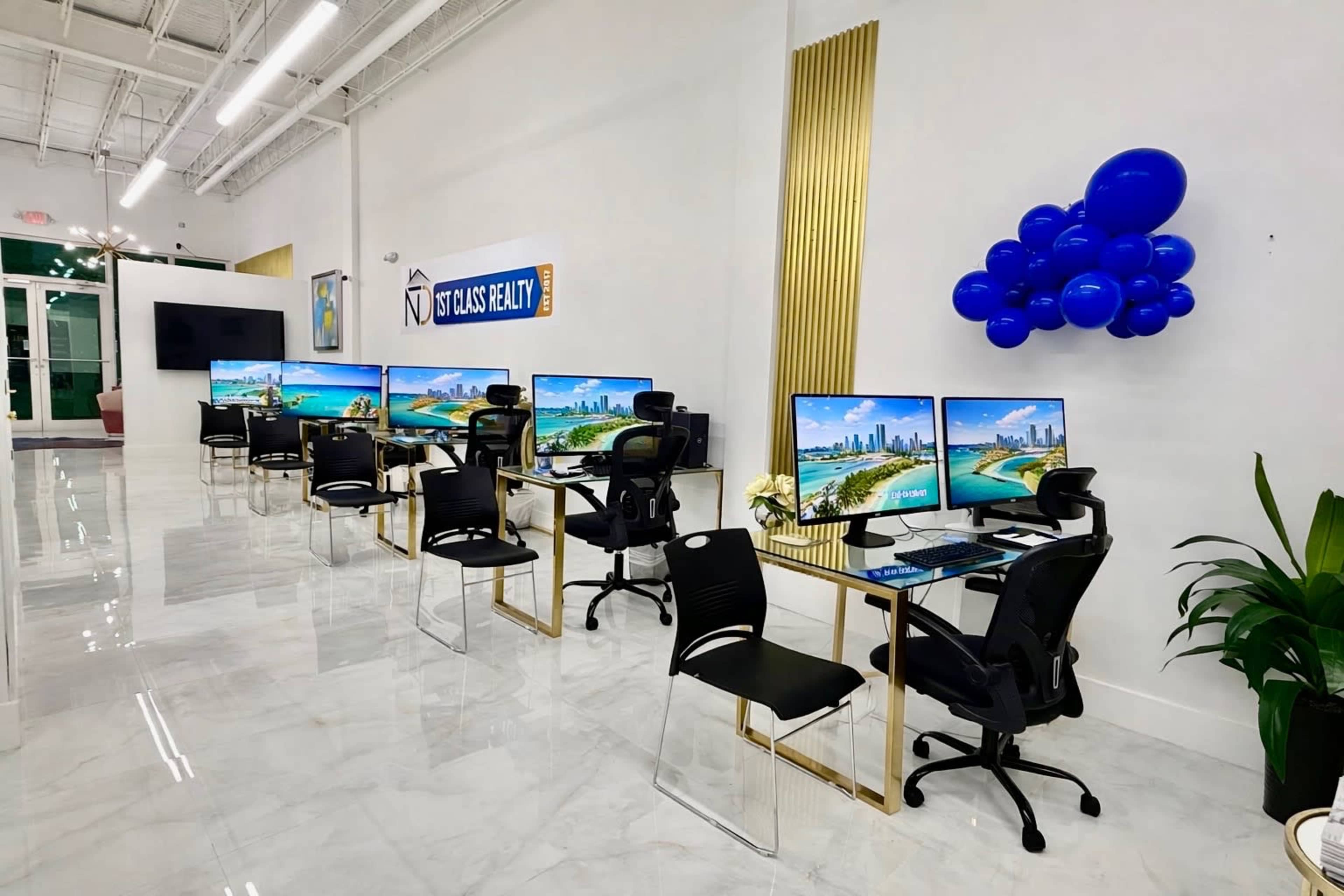 The image shows a modern office space with multiple workstations, each featuring a computer monitor and a black chair, against a backdrop of a tropical cityscape.