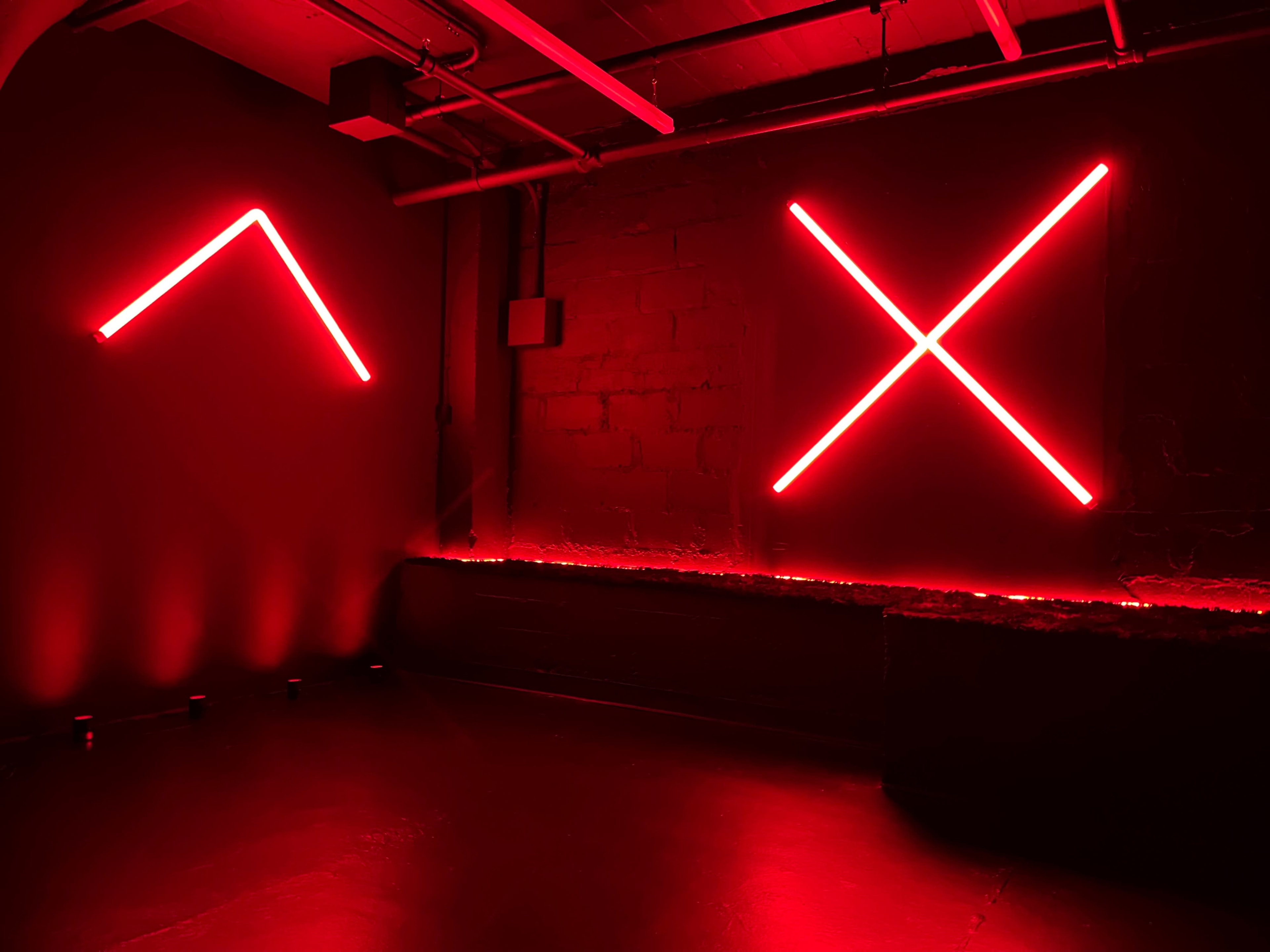 A dimly lit room with red neon lights forming geometric shapes on the walls.