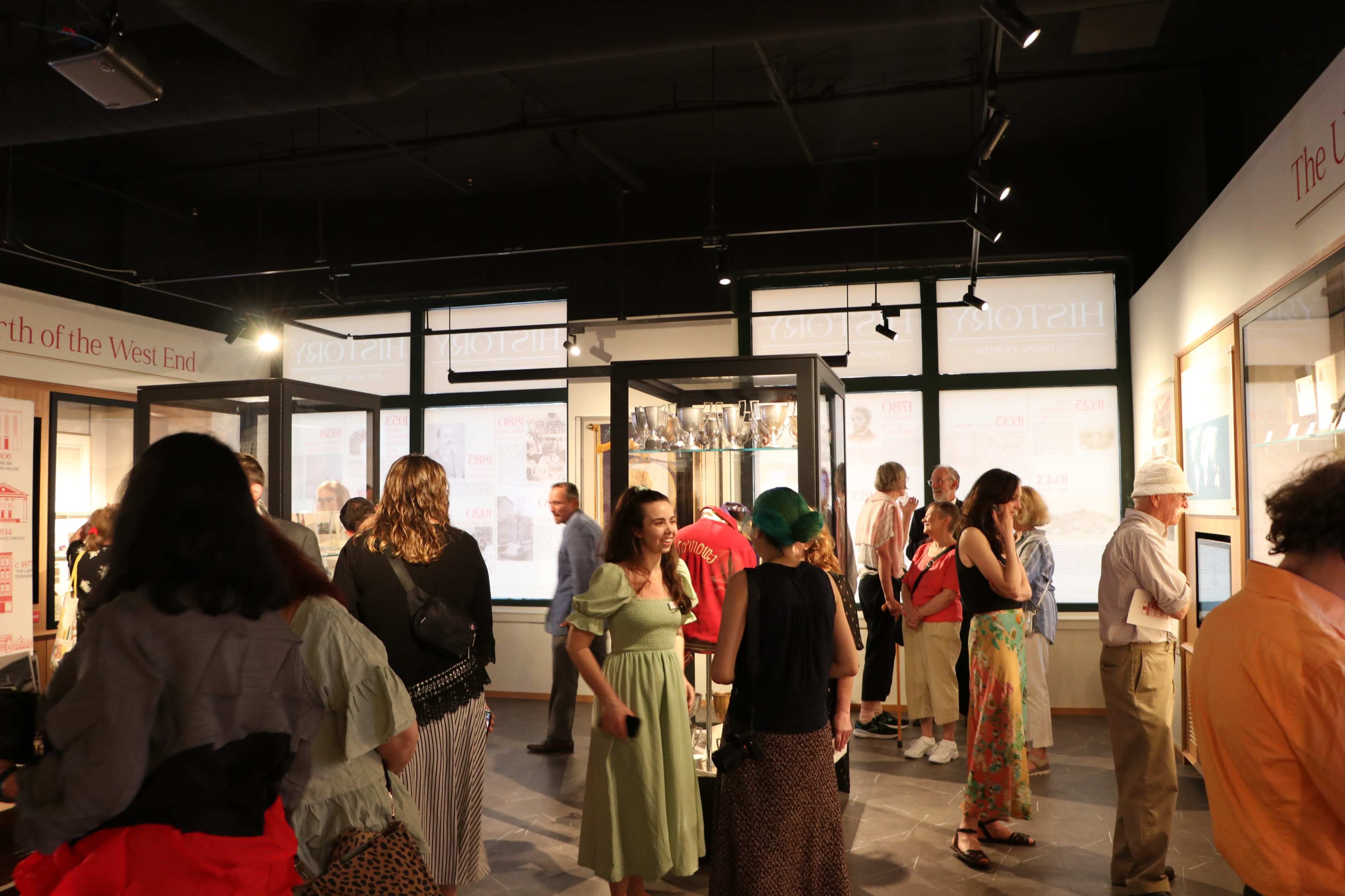 A group of people are exploring an exhibition space filled with display cases and informational panels.