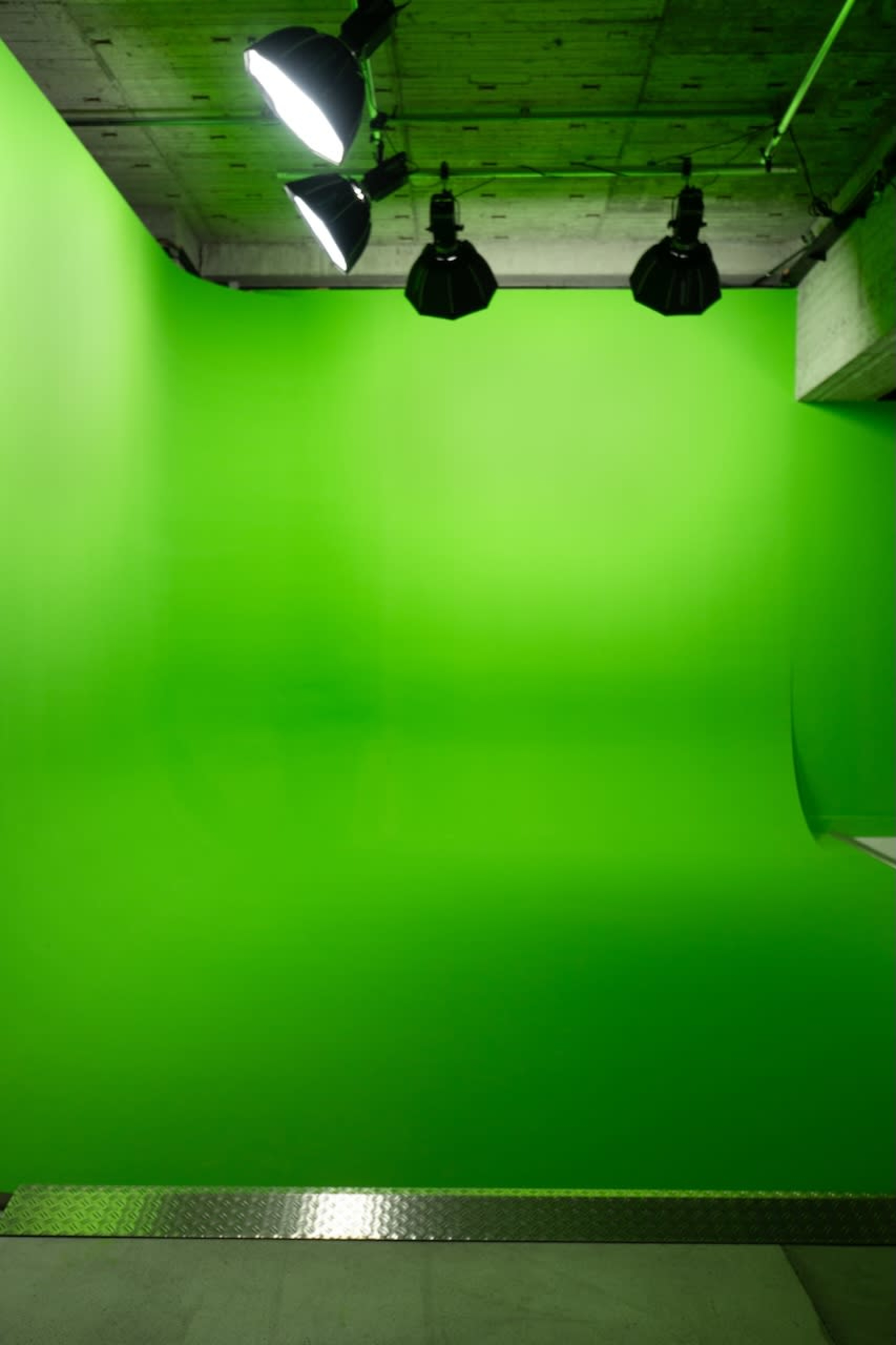 The image shows a green studio backdrop with several lights installed above it.