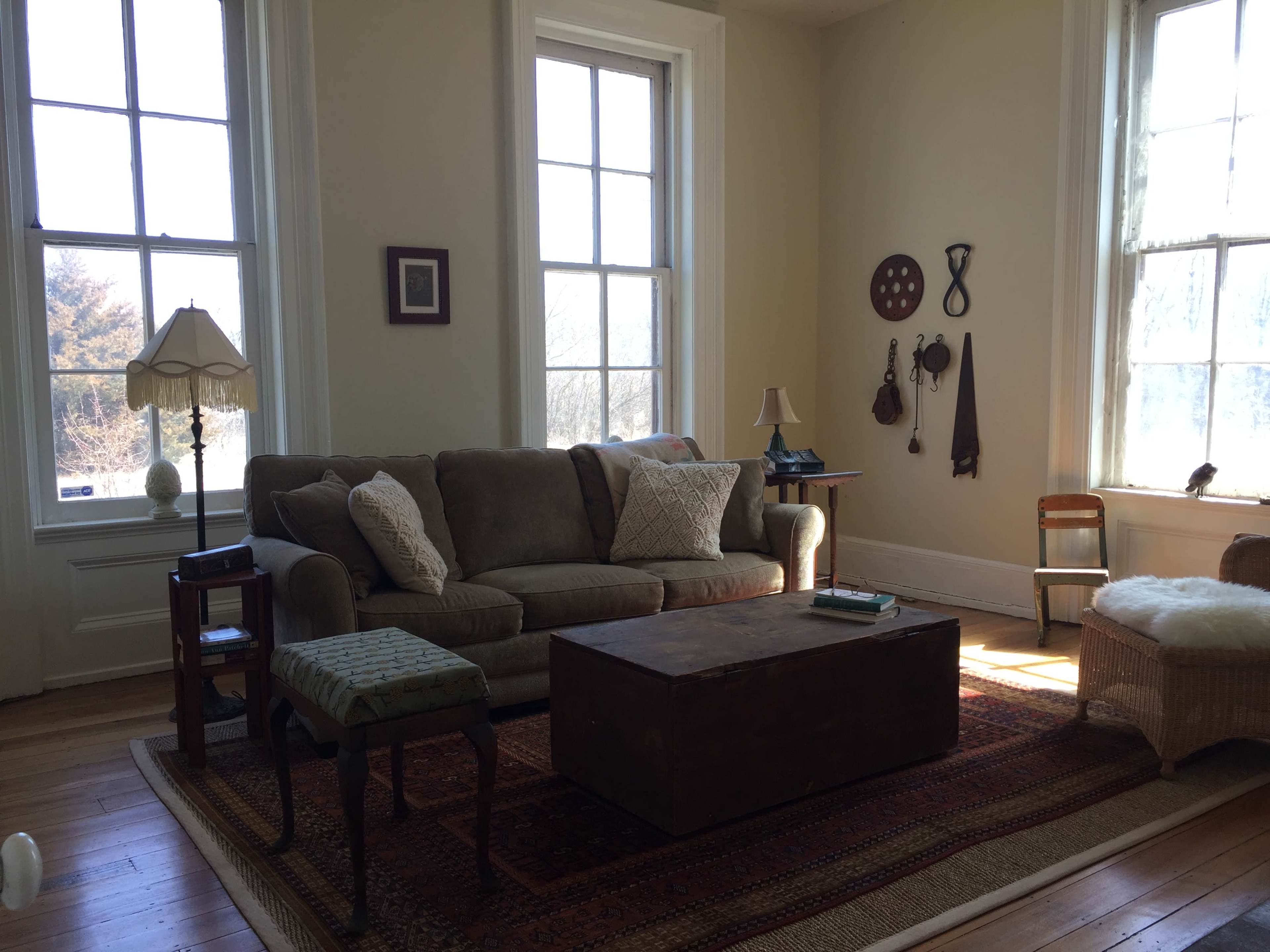 A cozy living room features a beige sofa, a wooden coffee table, and large windows allowing natural light to fill the space.