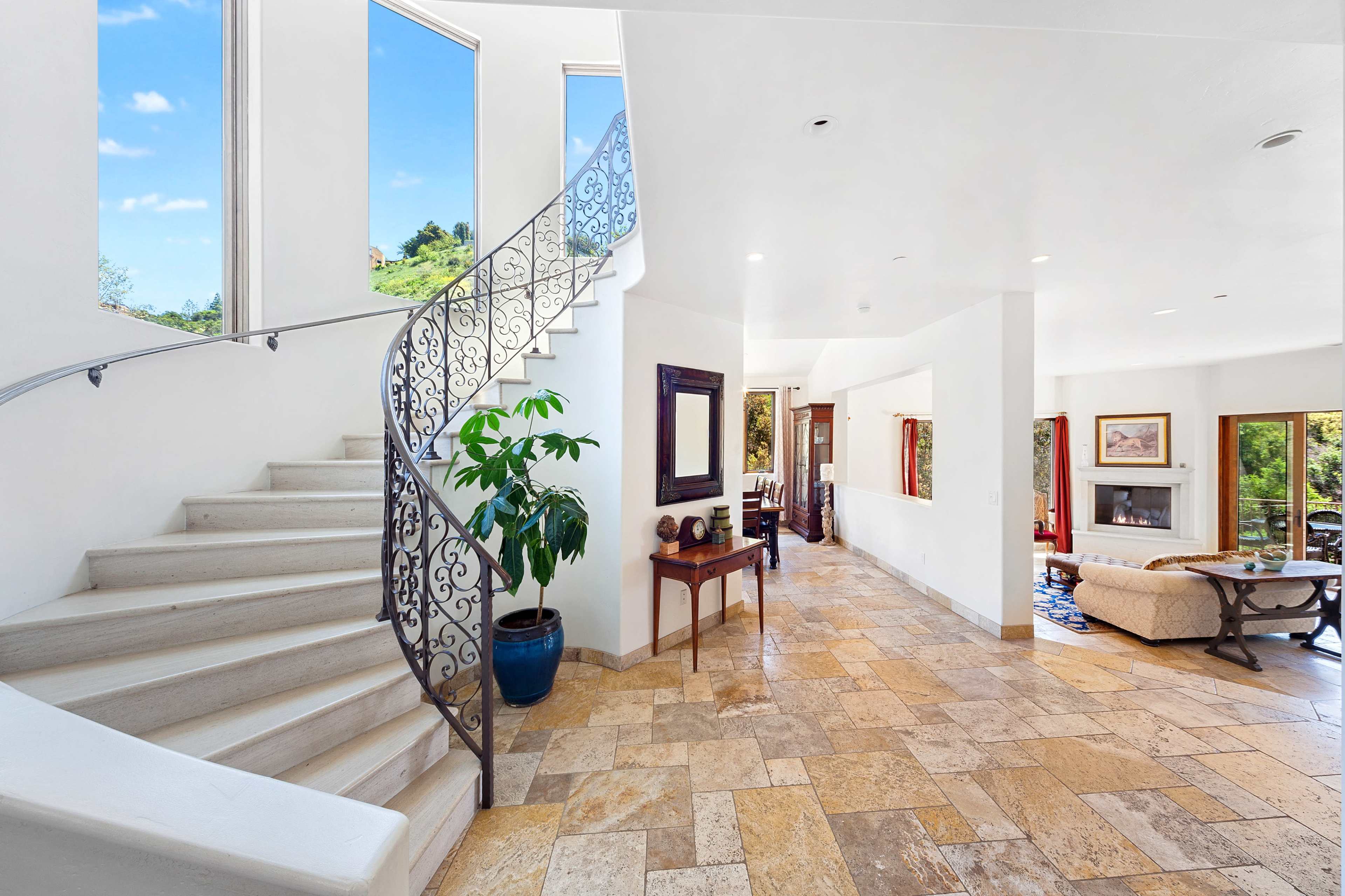 A spacious interior with a curved staircase, large windows, and a living area furnished with a sofa and coffee table.