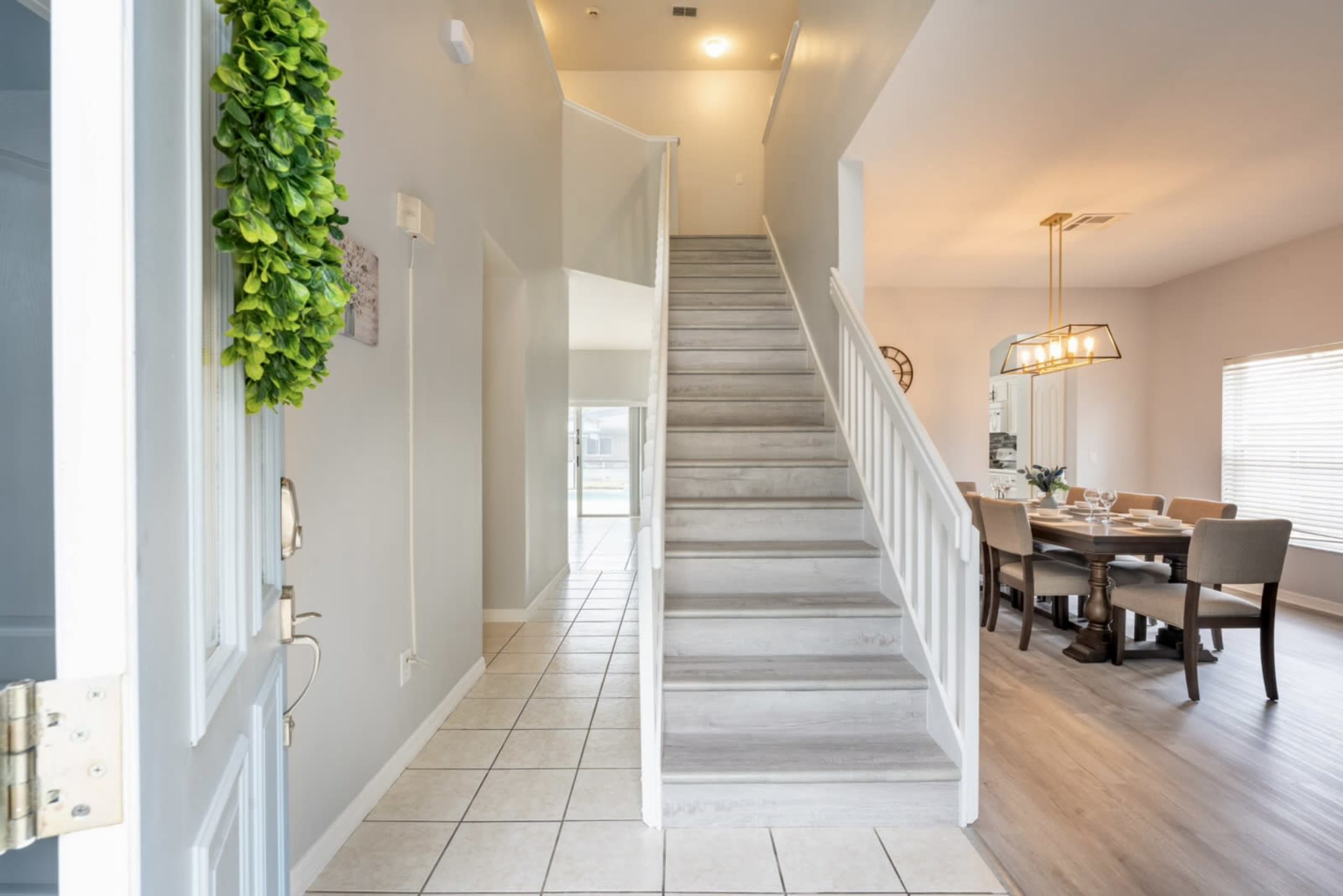 A well-lit entryway leading to a staircase, with a dining area visible in the background.