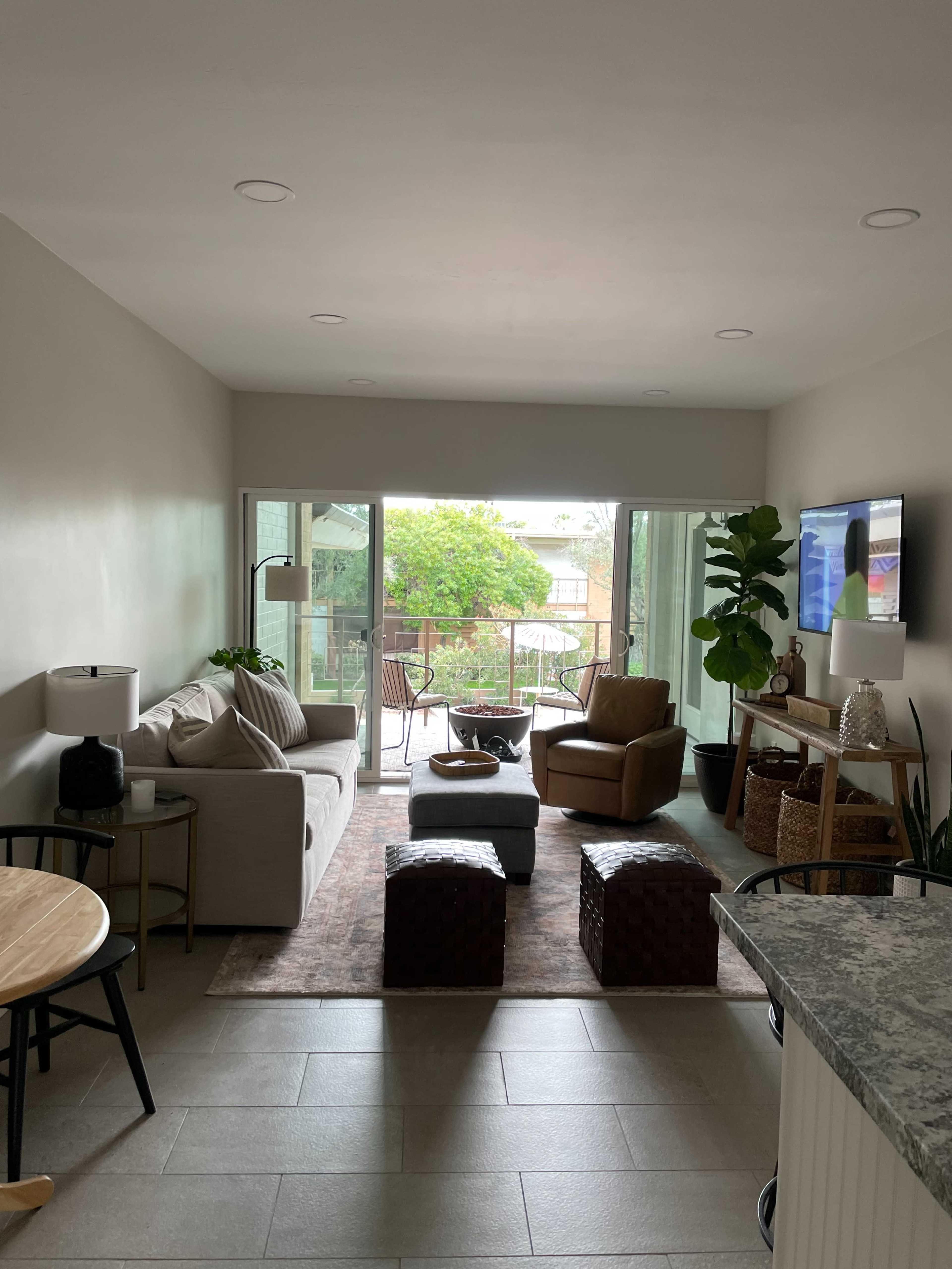 A modern living room with a sofa, a chair, a coffee table, and sliding glass doors leading to a patio area.
