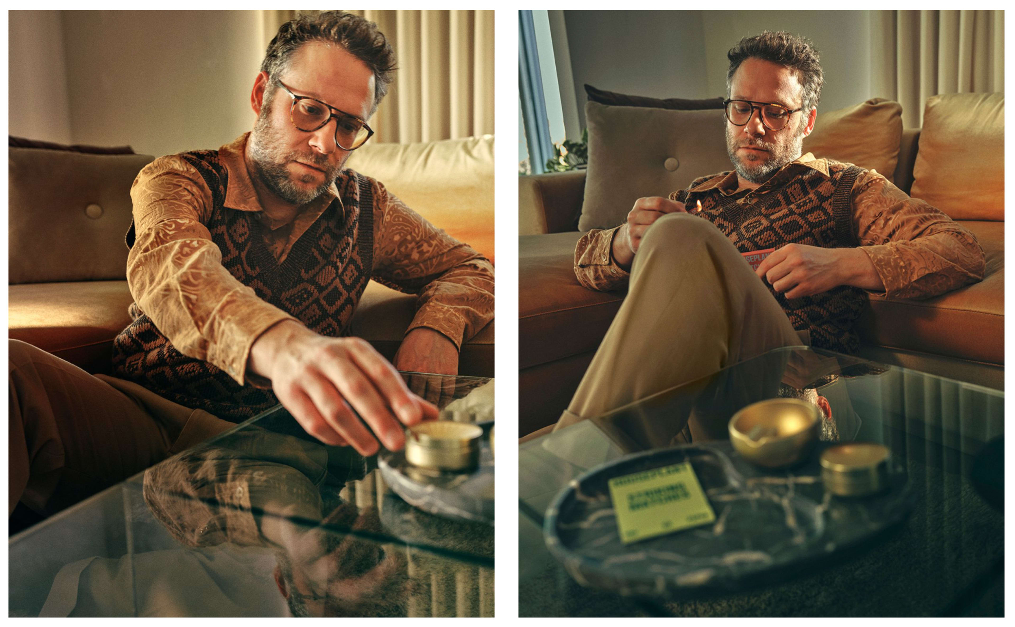 A man in glasses sits on a couch, reaching for a small container on a glass table.