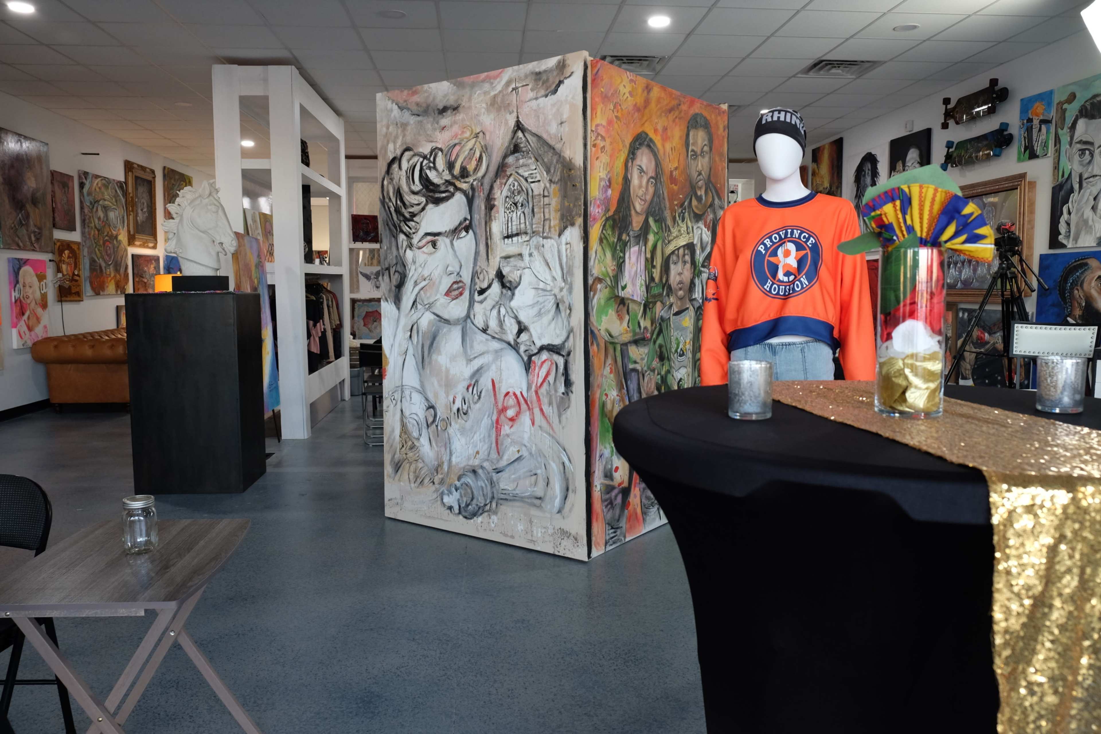 An art gallery space with vibrant murals, a display of clothing, and various artistic installations.