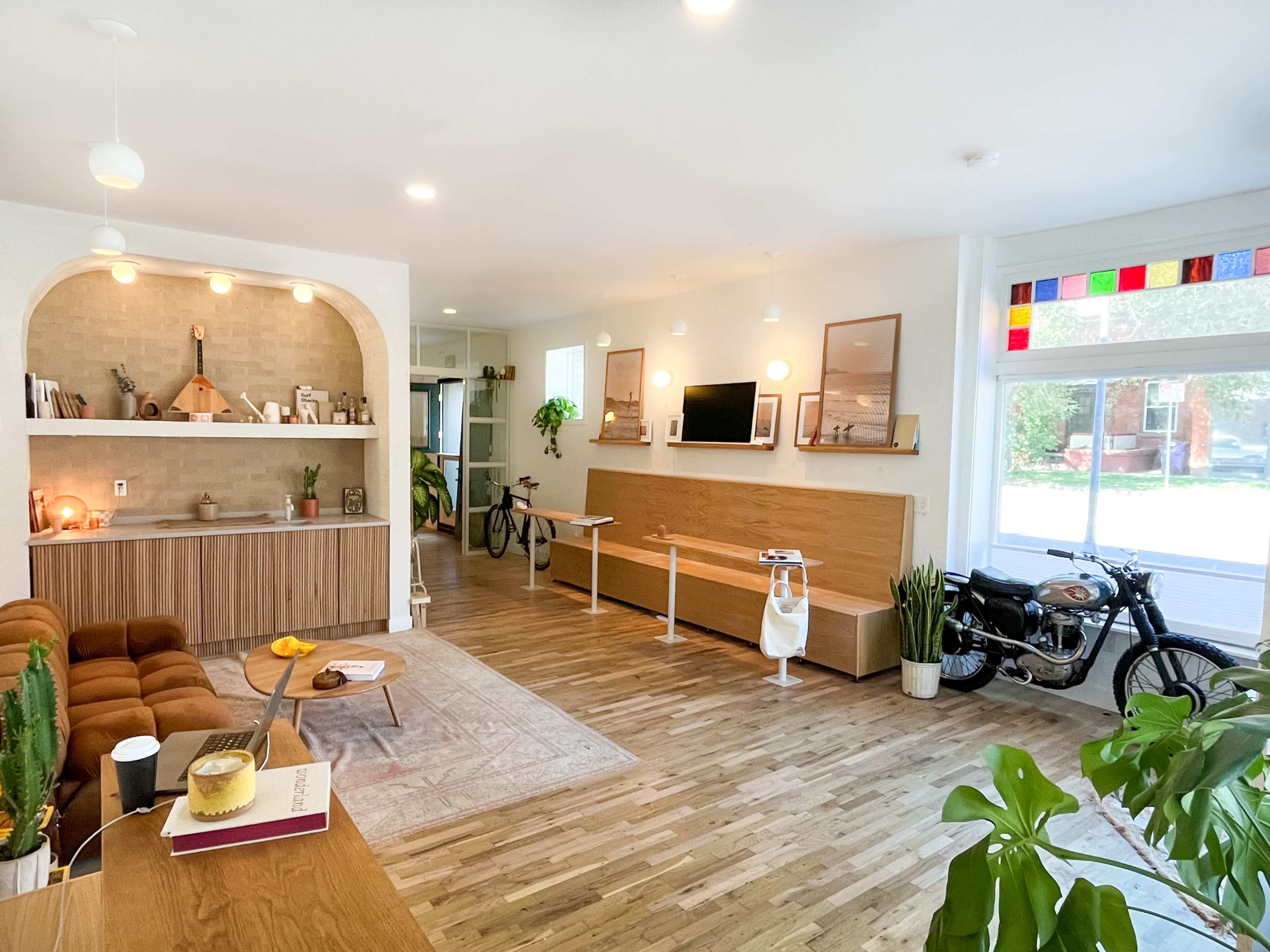 A modern living space featuring a wooden floor, a cozy seating area, a bike, and a wall-mounted television.