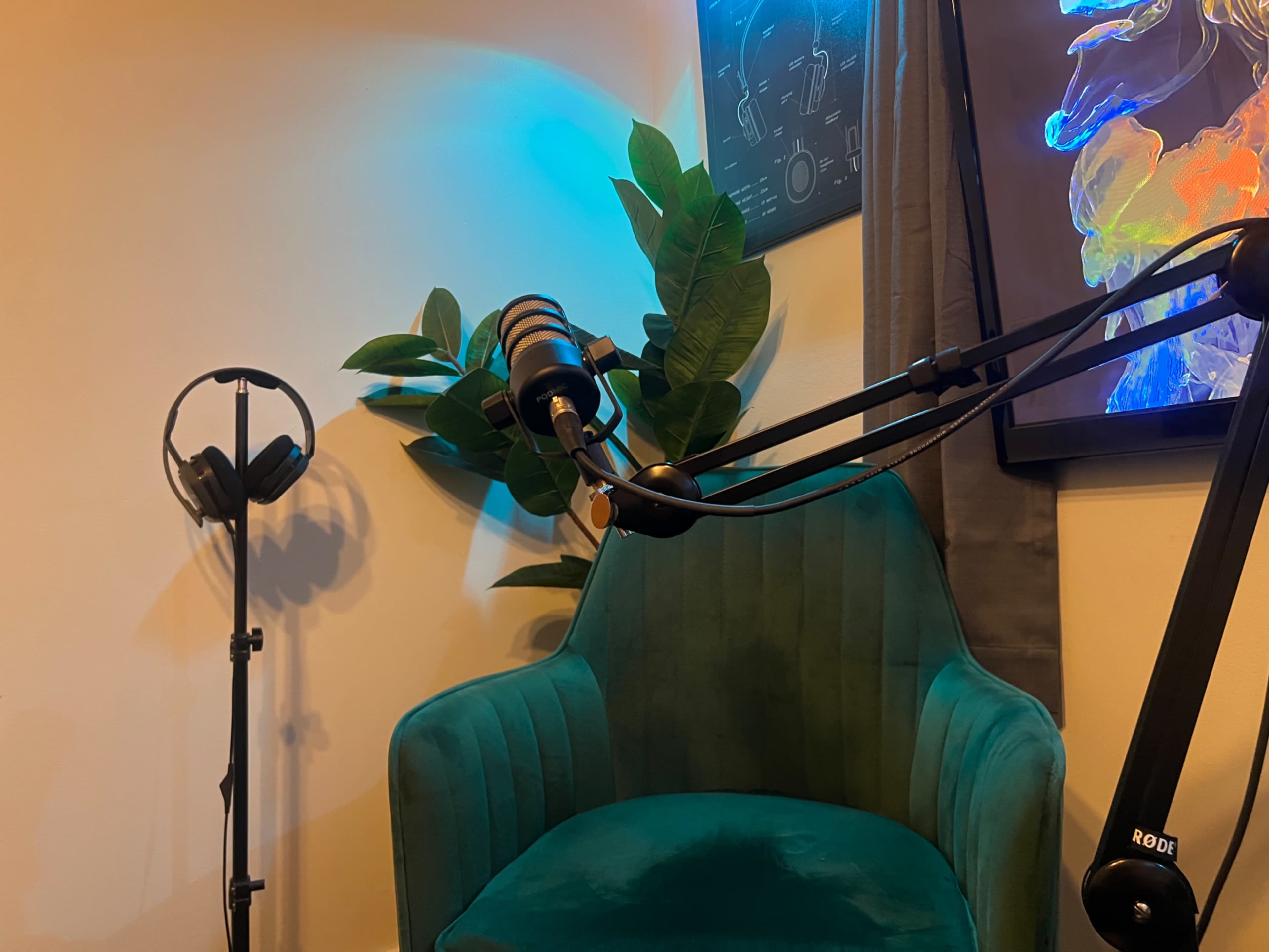 A green velvet chair is positioned next to a floor stand with headphones, set against a wall adorned with plants and colorful artwork.