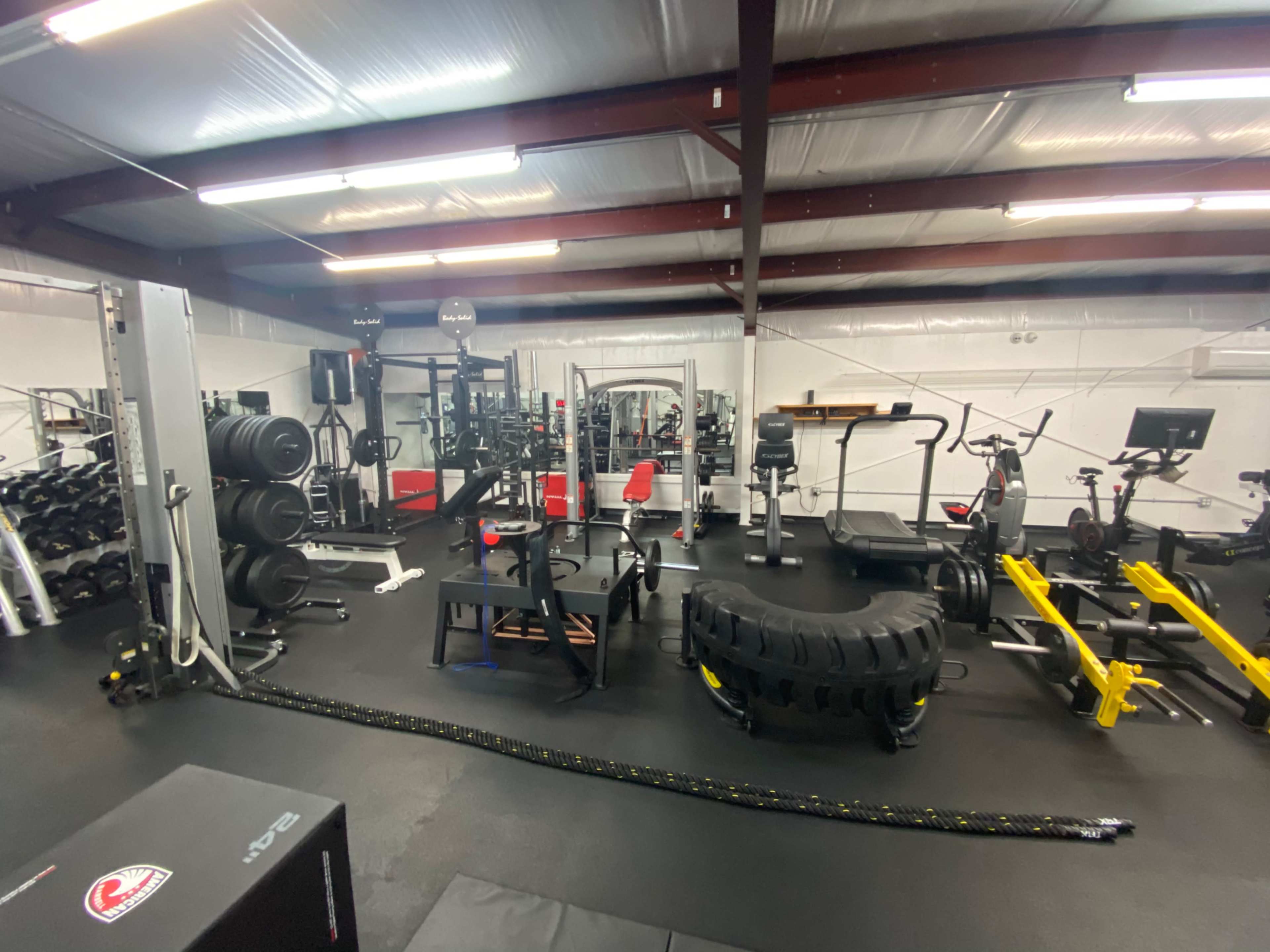 A well-equipped gym featuring various workout machines, free weights, and fitness equipment arranged in a spacious, organized layout.