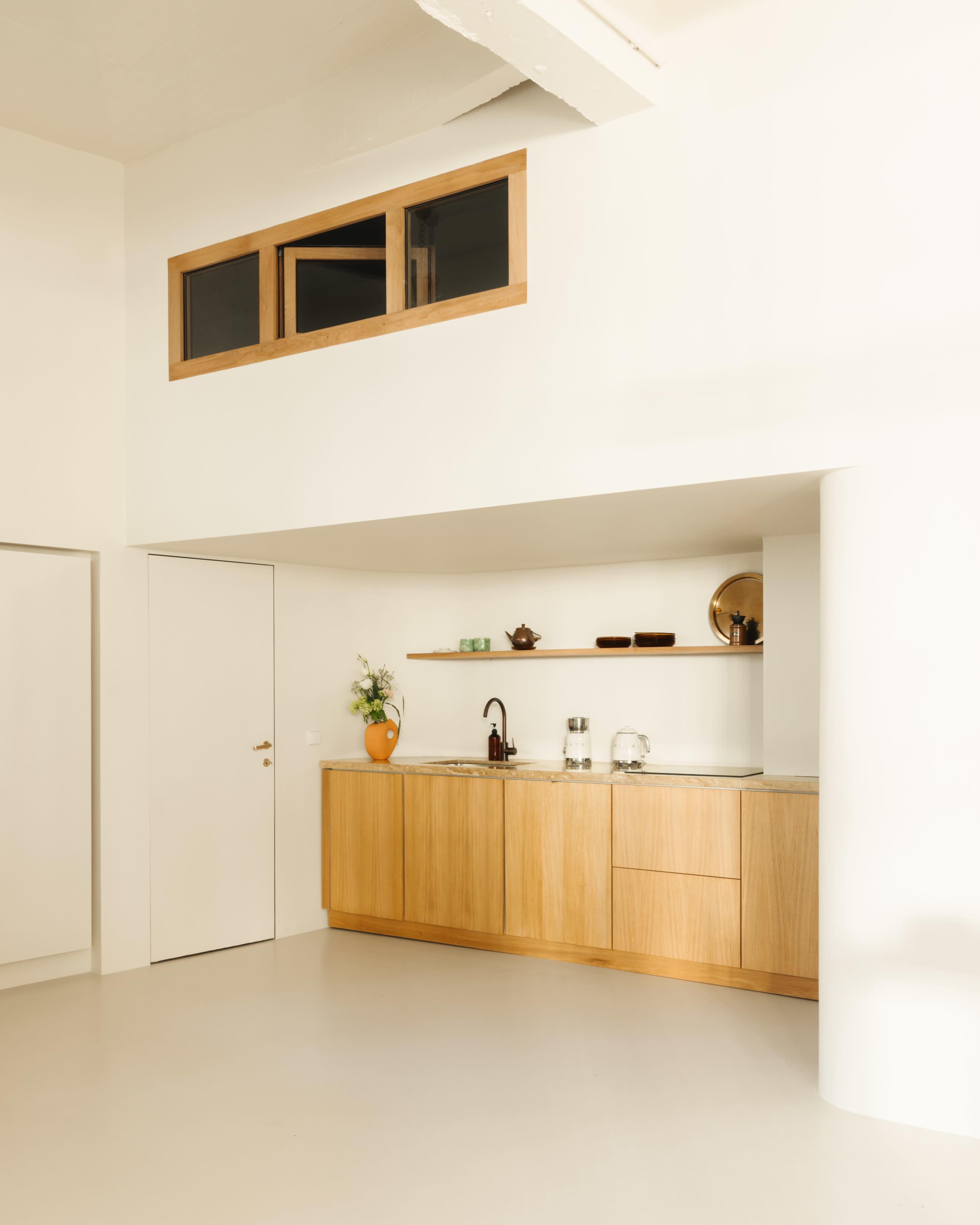 A modern kitchen with wooden cabinetry, a sink, and minimal decorative items against a white wall.